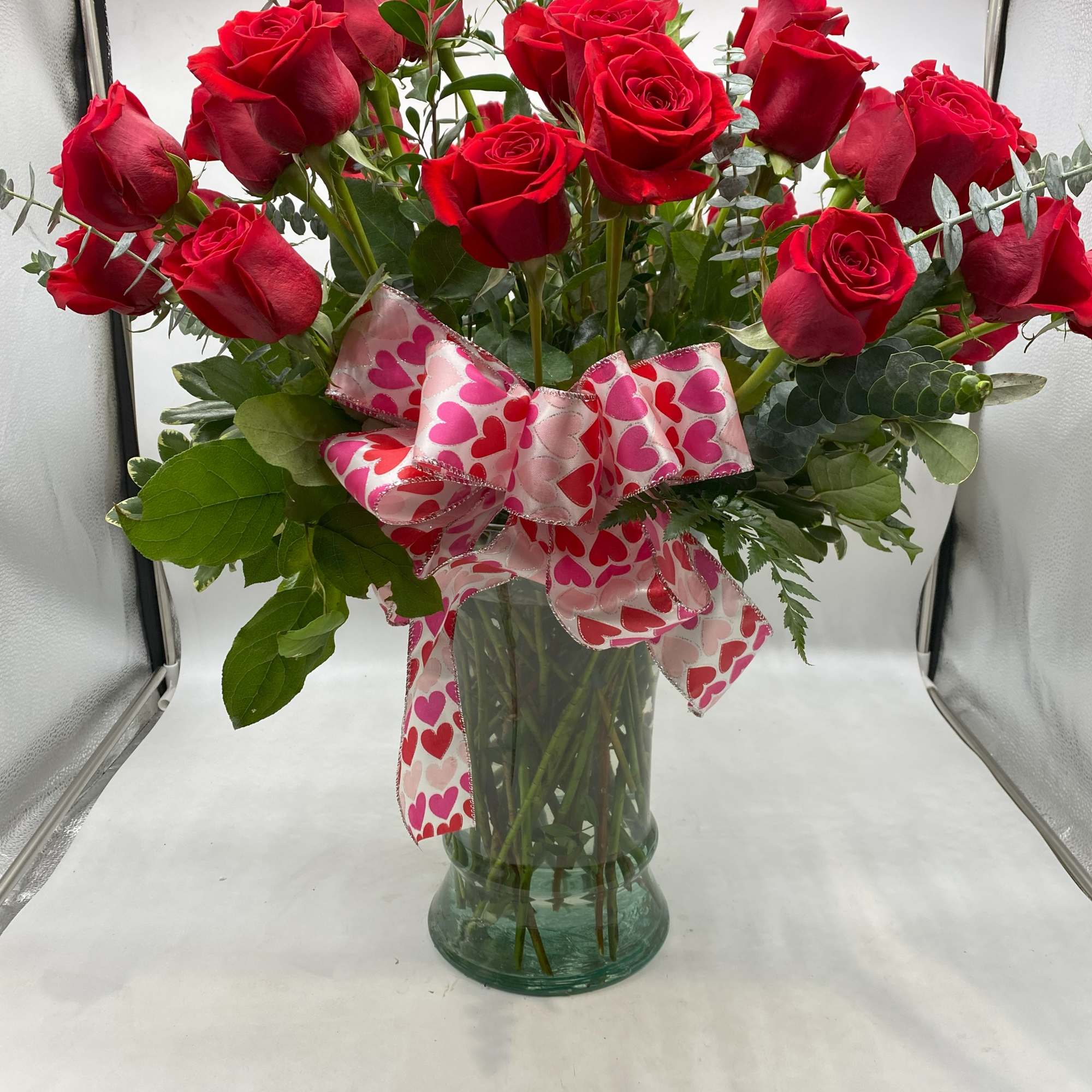 Three dozen long-stemmed red roses in a striking glass vase. 
(Ribbon will