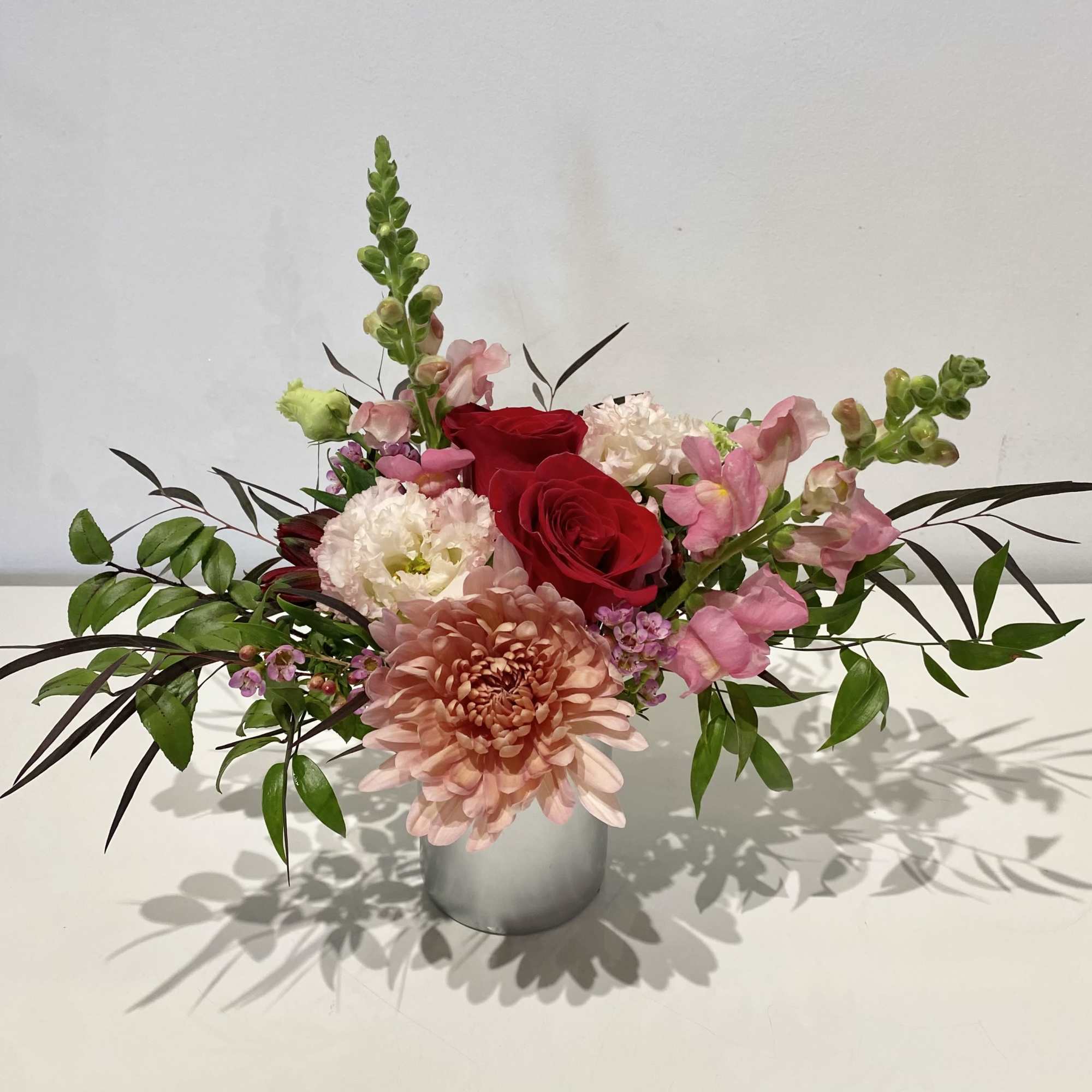 A glass cup holding an array of fresh cut Florals in seasonal