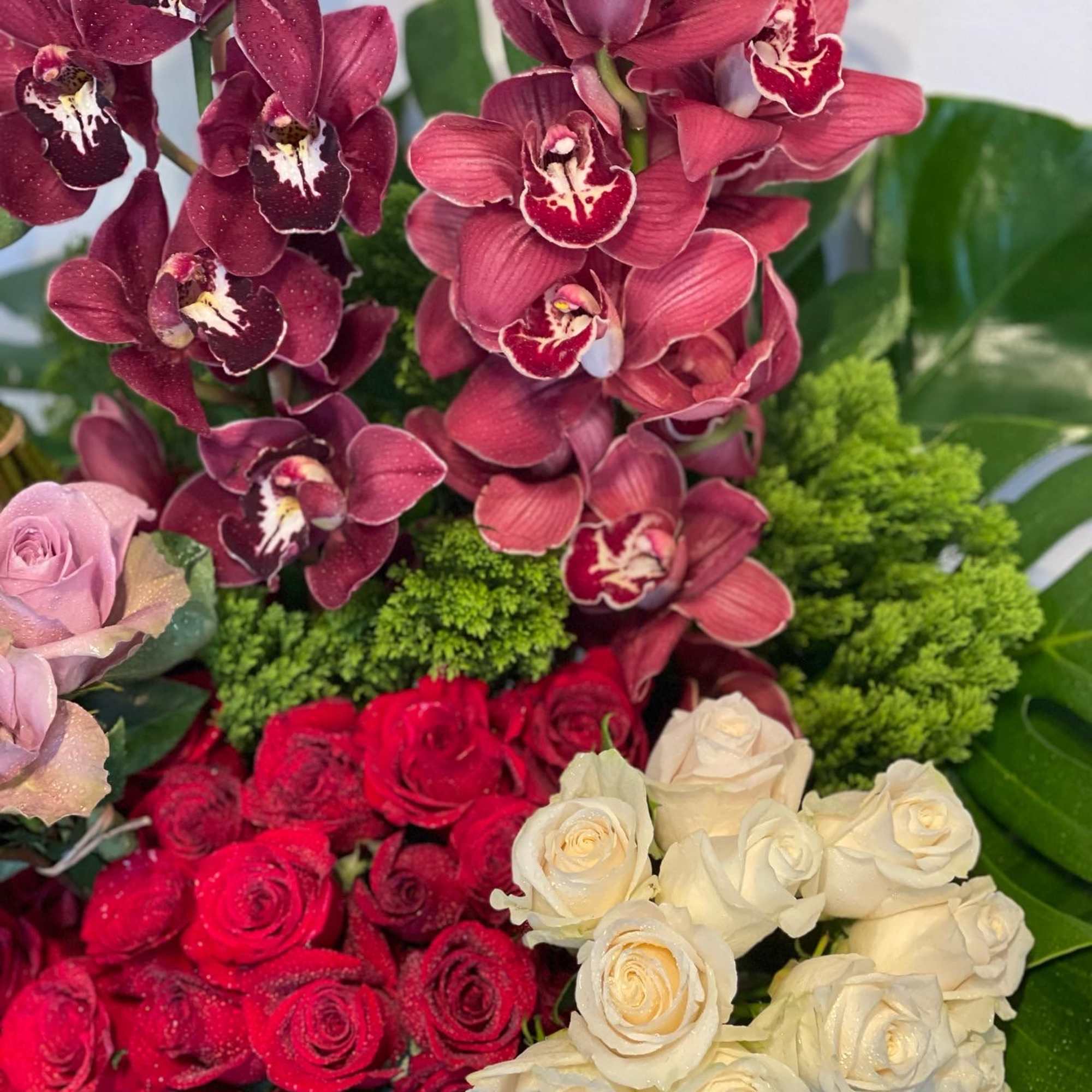 Beautiful floral garden arrangement featuring red and white roses, tulips, cymbidium orchids