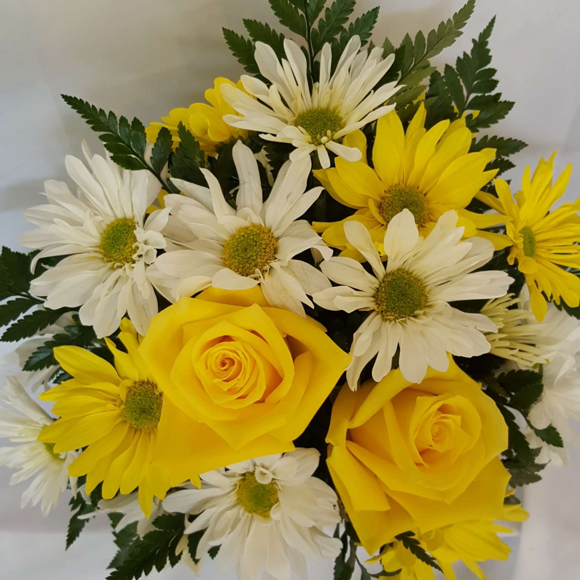 Yellow and white daisies fill this smiley face mug with two roses