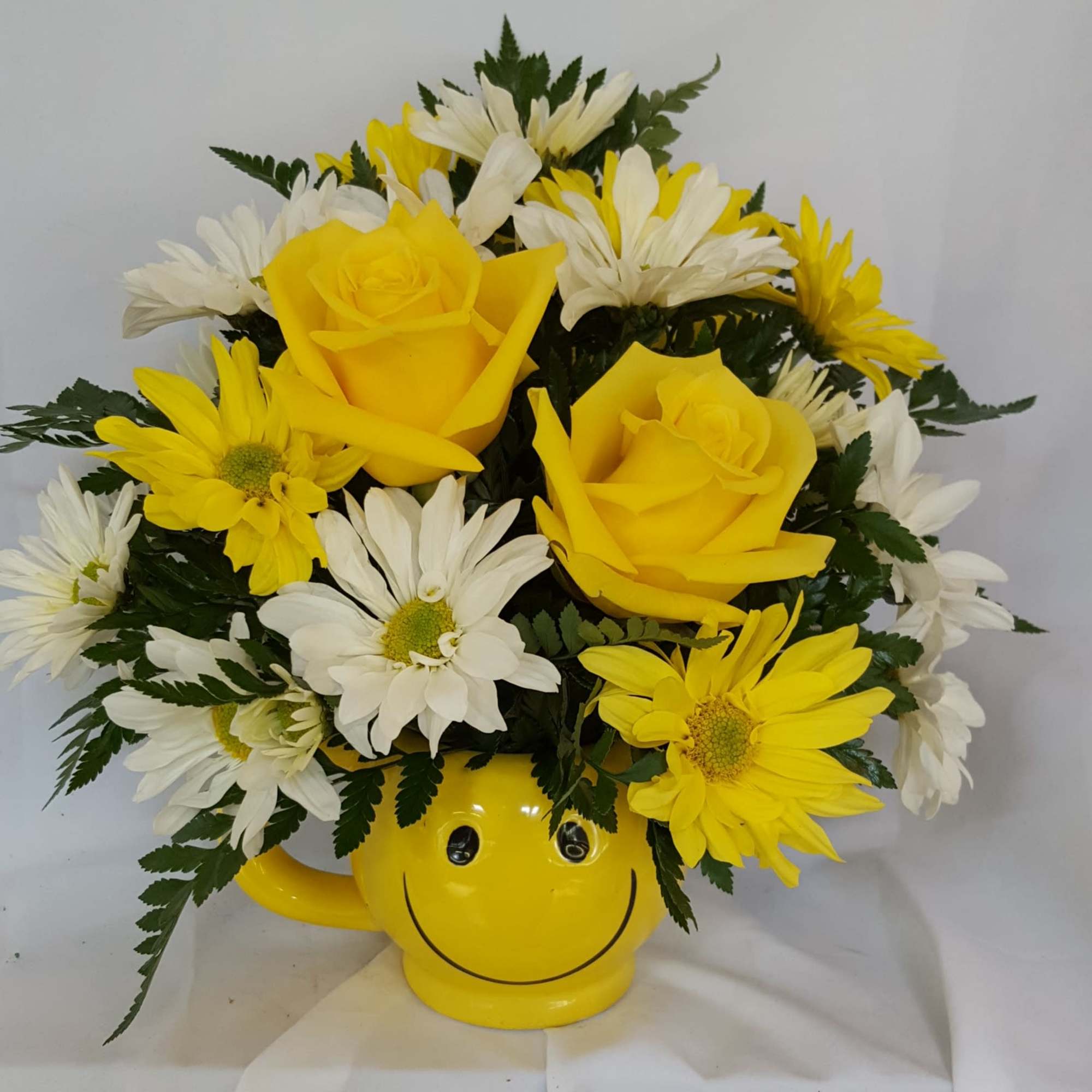 Yellow and white daisies fill this smiley face mug with two roses