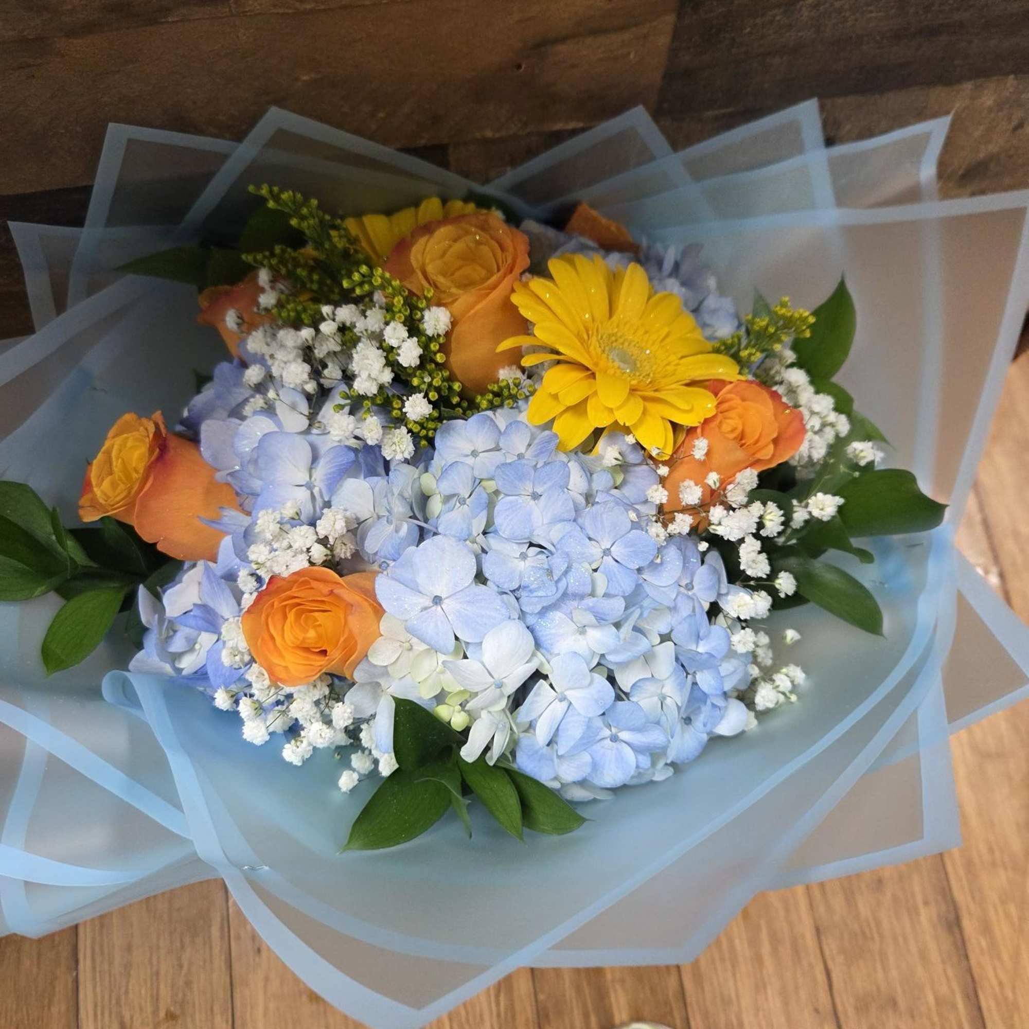 blue hydrangeas, orange roses, yellow gerberas fillers and greens