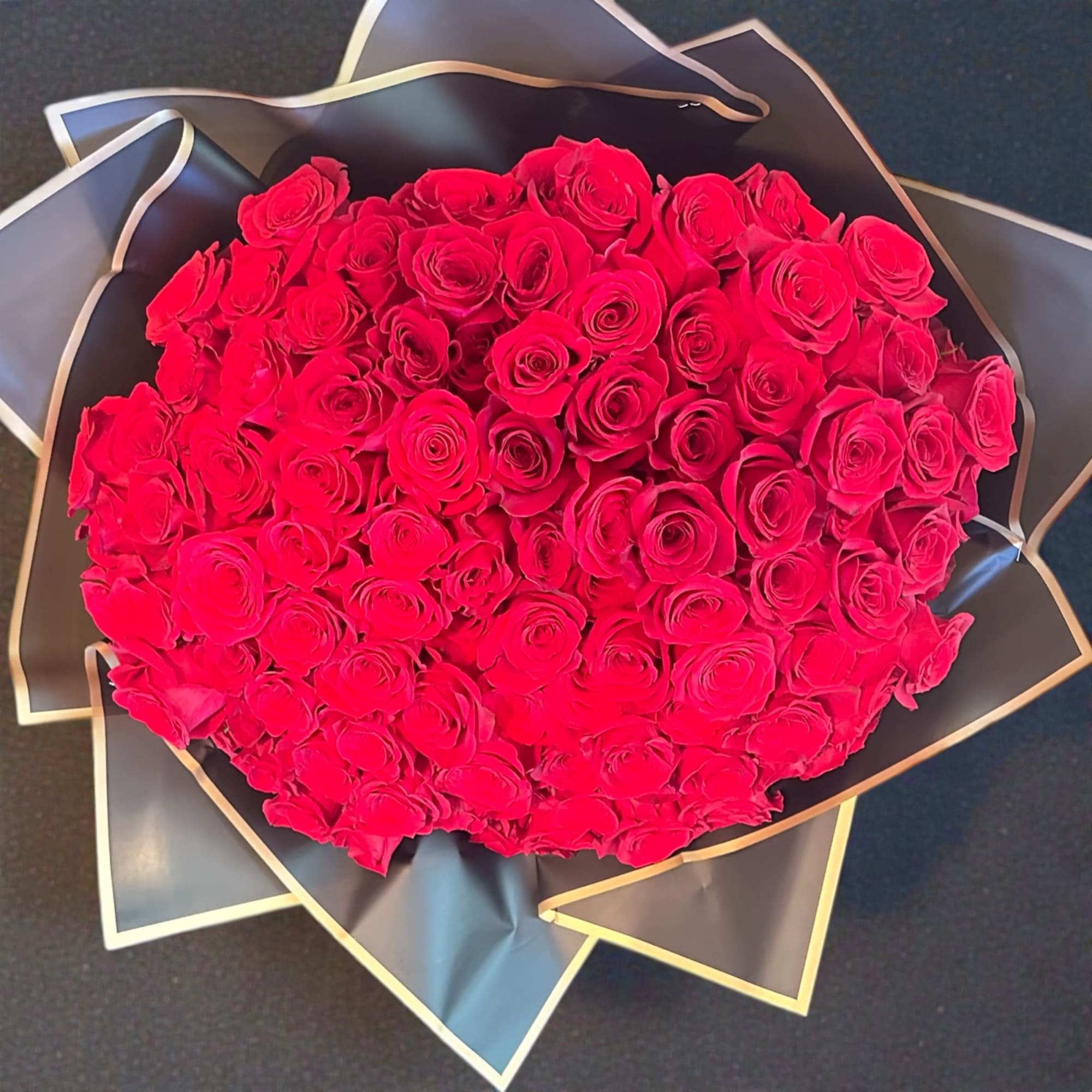 The Ramo Buch&oacute;n 100 Wrapped Roses Arrangement is a luxurious floral statement