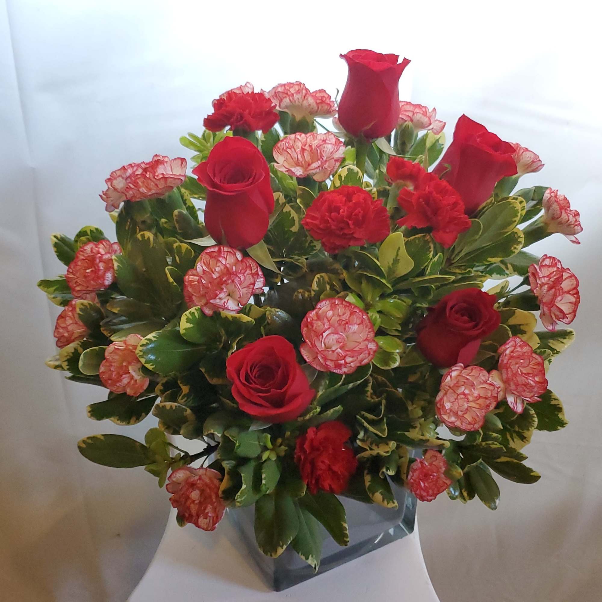 Lush red roses, fresh winter greens and a festive, gold mirrored glass