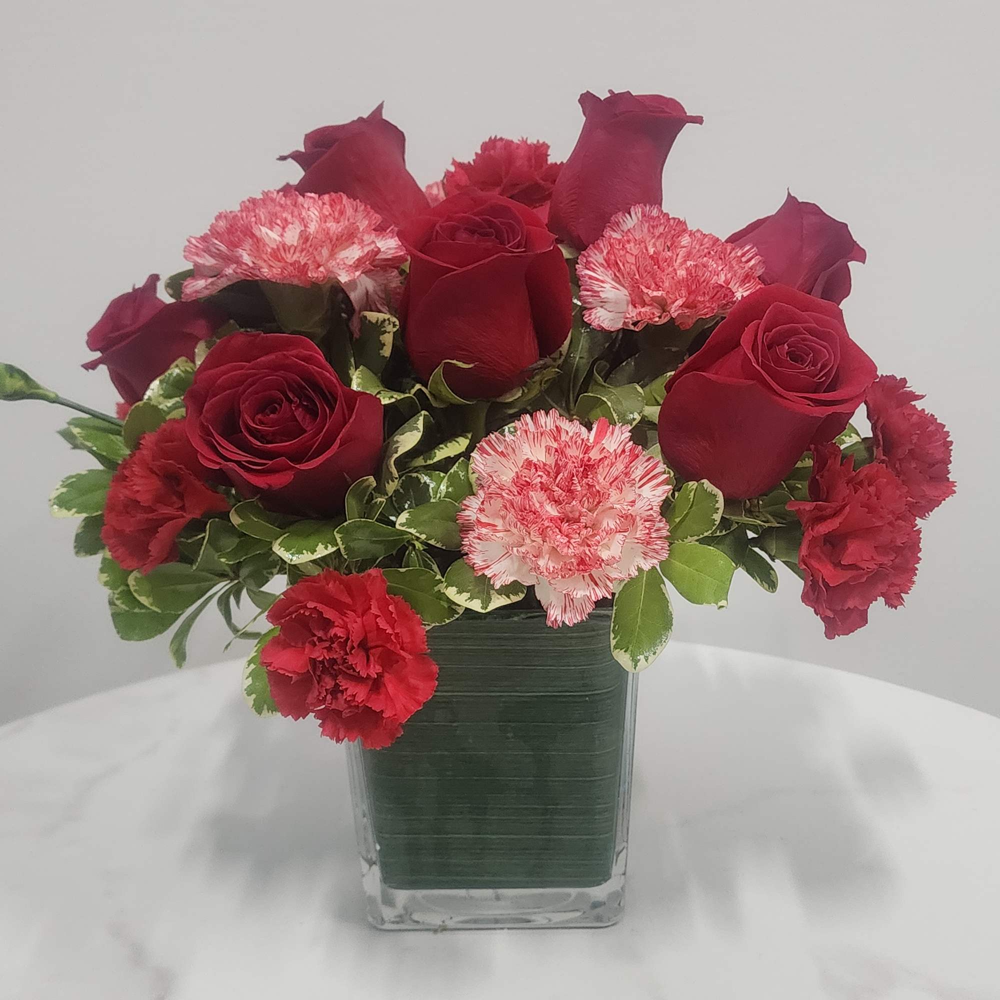 Lush red roses, fresh winter greens and a festive, gold mirrored glass