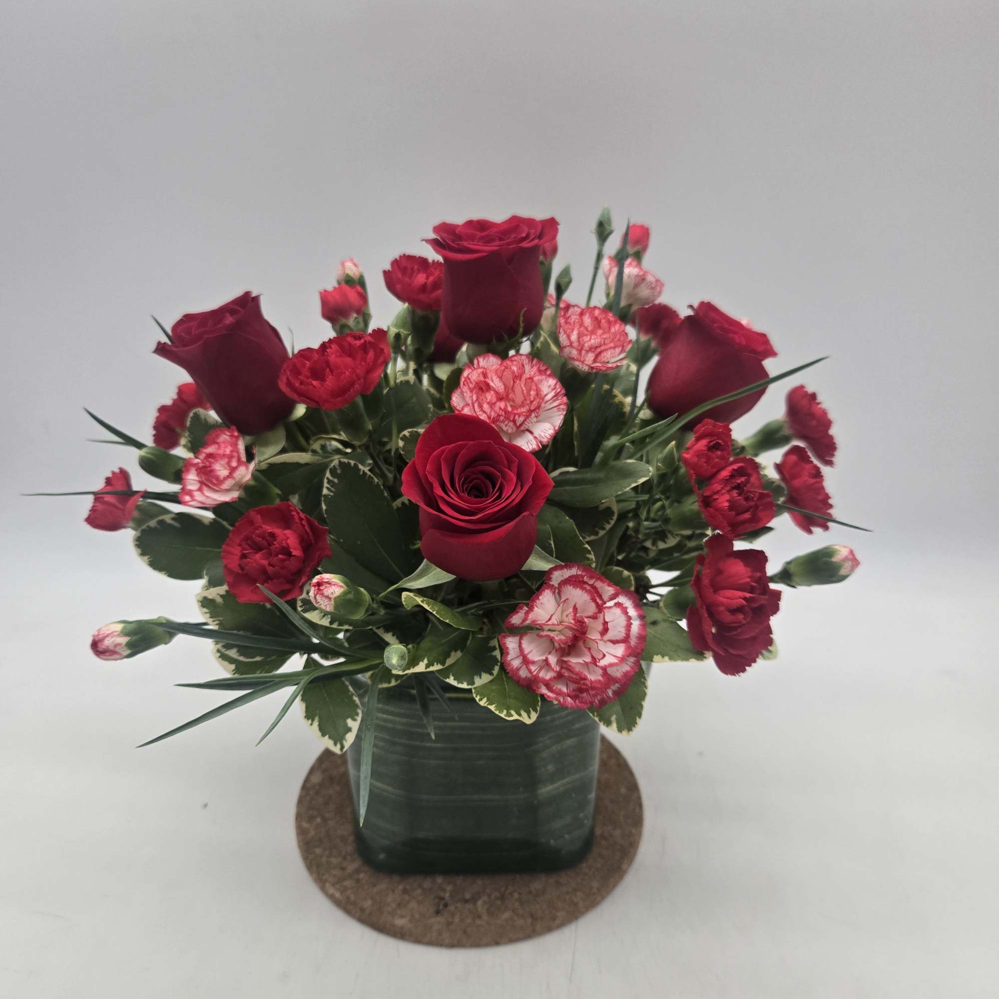 Lush red roses, fresh winter greens and a festive, gold mirrored glass