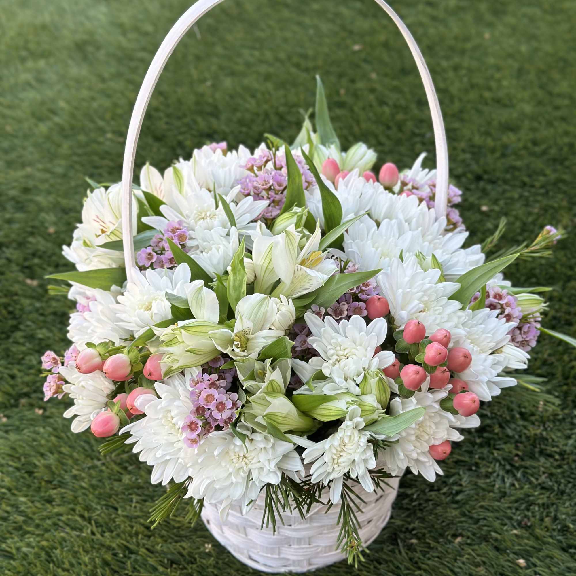 A miniature basket filled with a soft mix of fresh blooms &mdash;