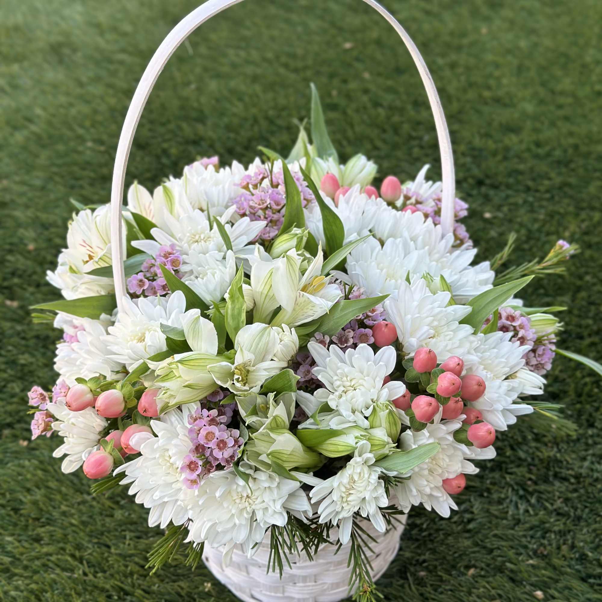 A miniature basket filled with a soft mix of fresh blooms &mdash;