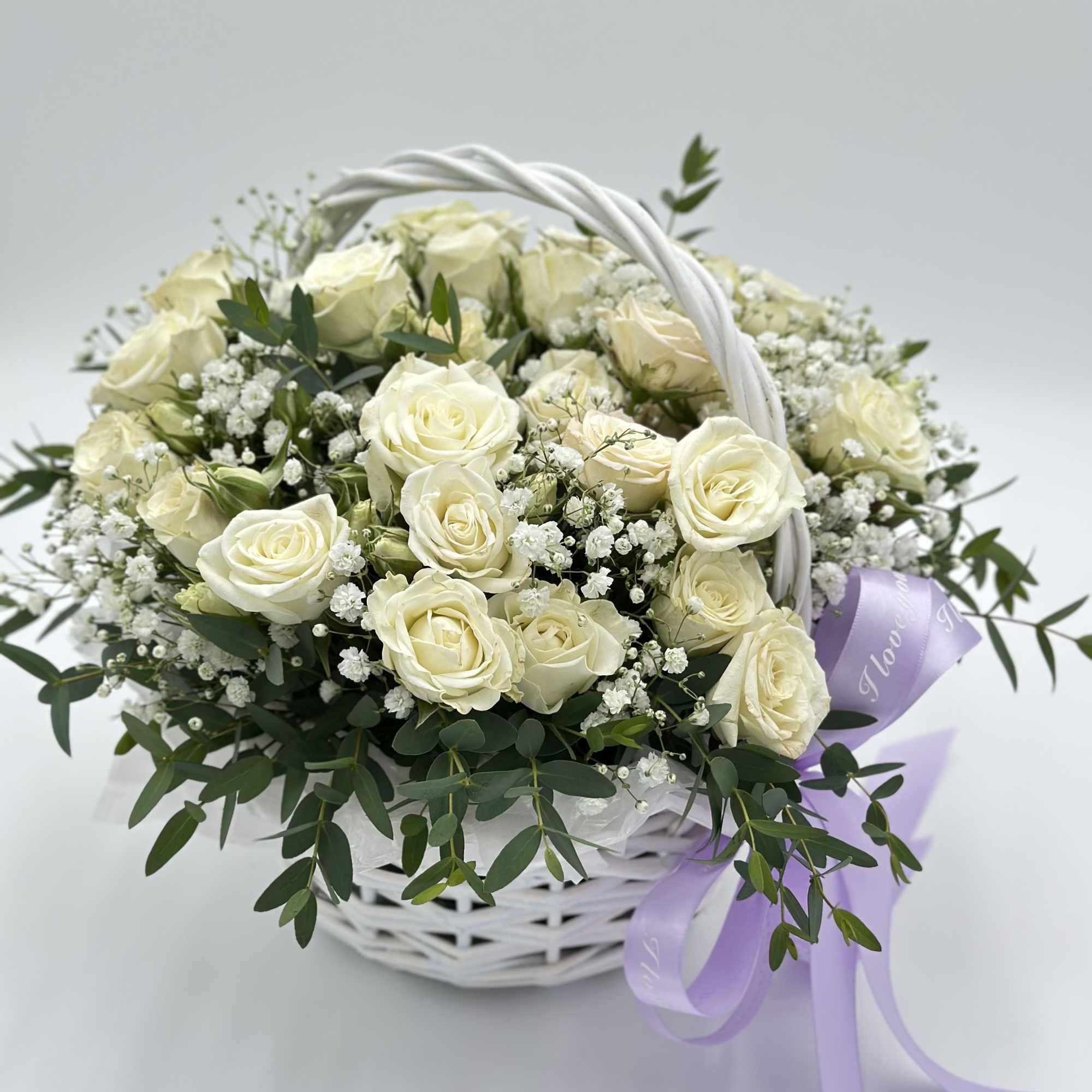 A delicate basket filled with white spray roses, woven as if from