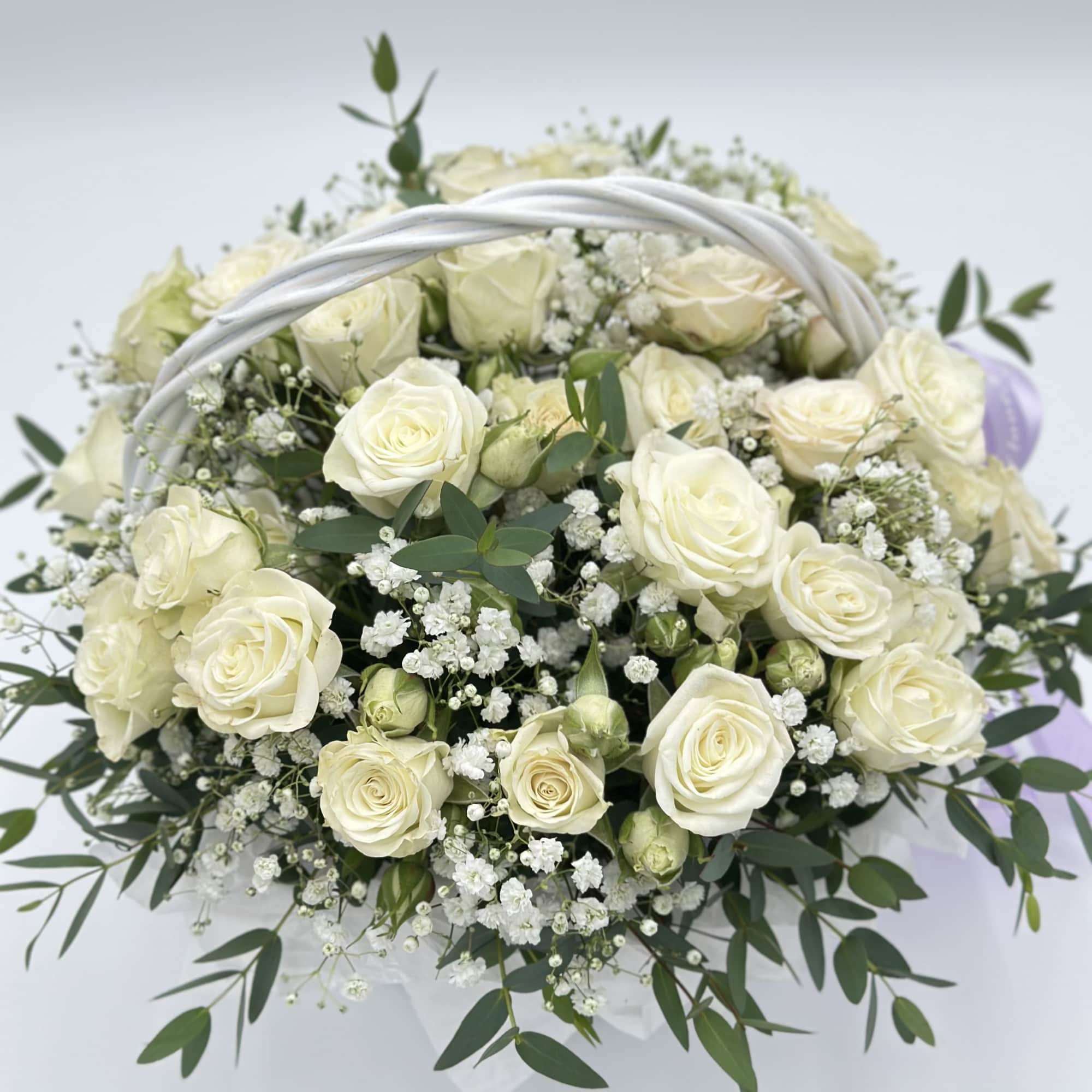 A delicate basket filled with white spray roses, woven as if from