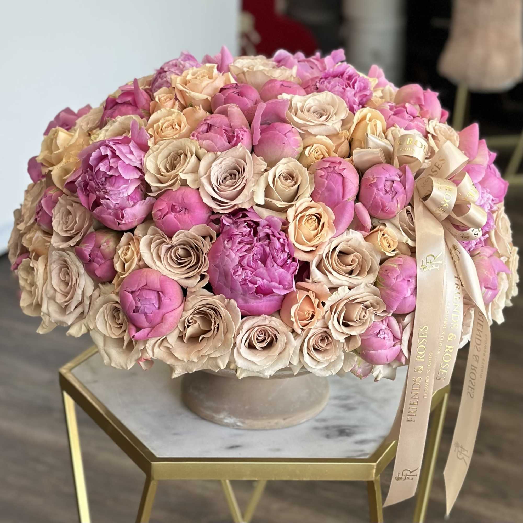 A vintage vase filled with bold peonies and quicksand roses - a