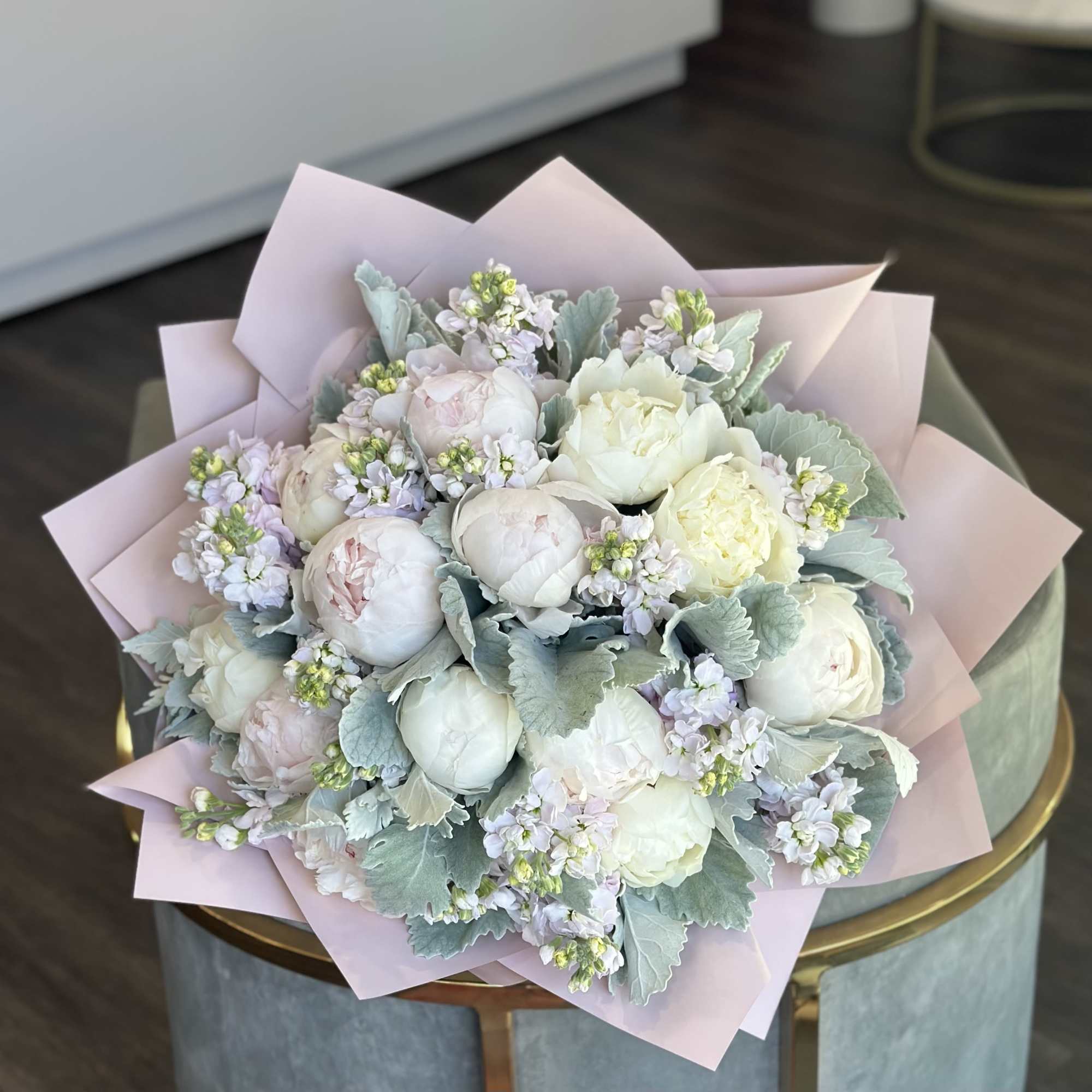 A hand-tied bouquet with pastel peonies features full, delicate blooms arranged in