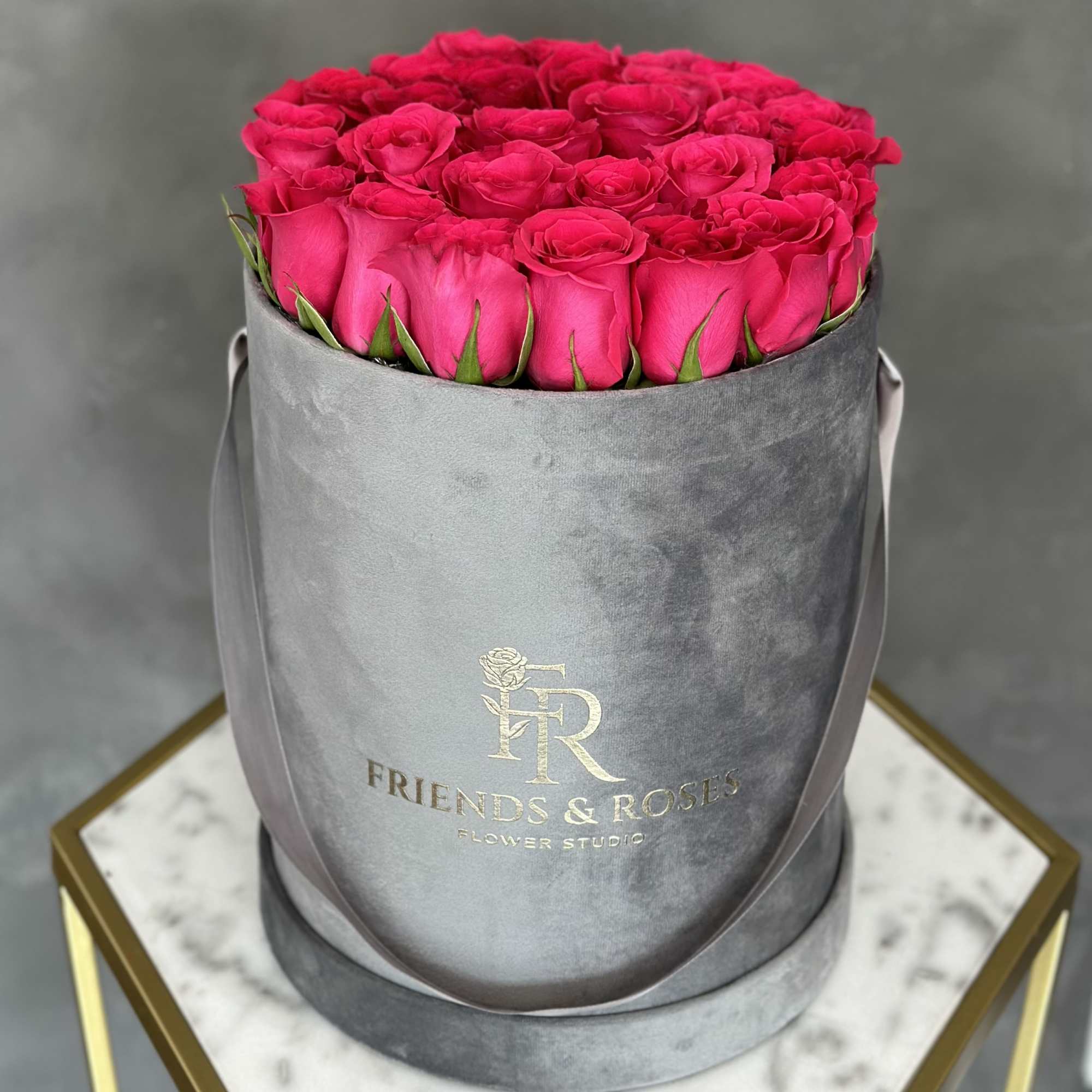 Hot pink roses are arranged in a flat shape inside our signature