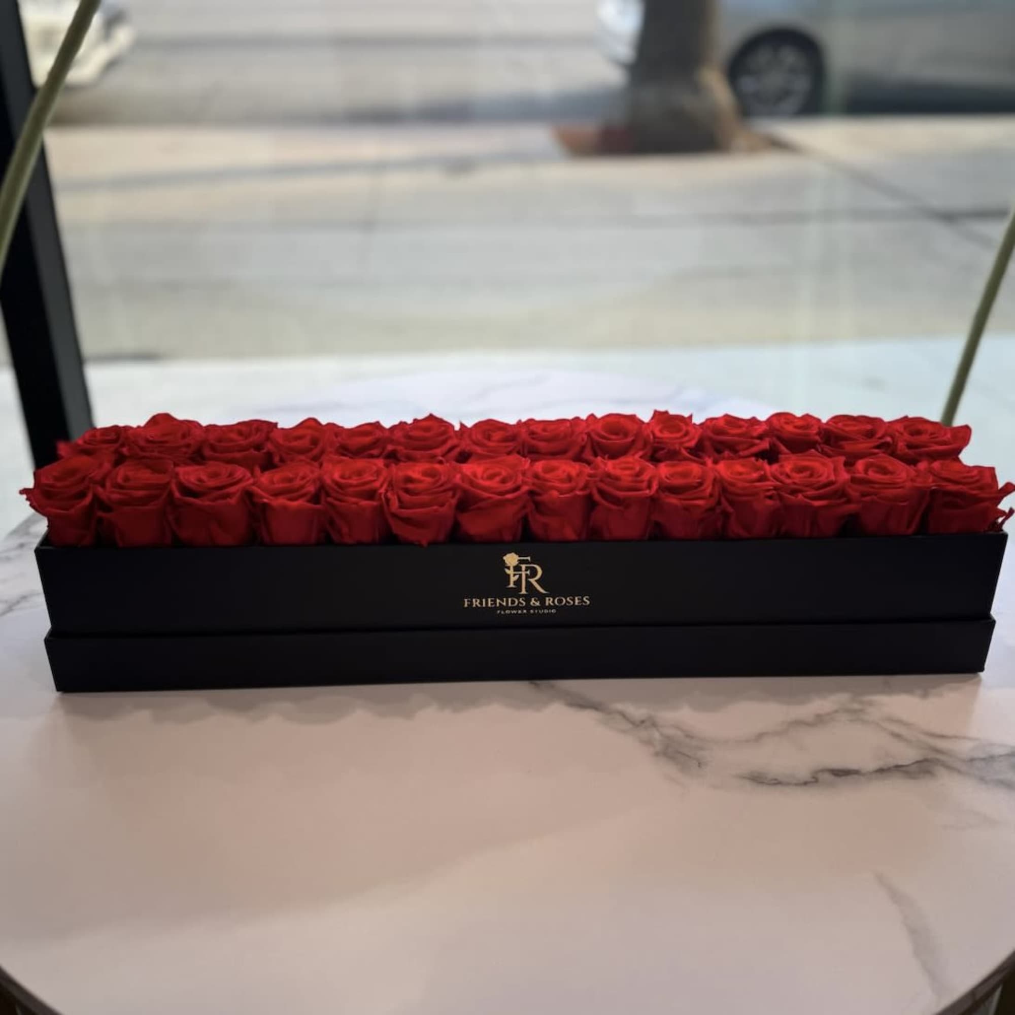 A sleek long black box filled with approximately  28 preserved red