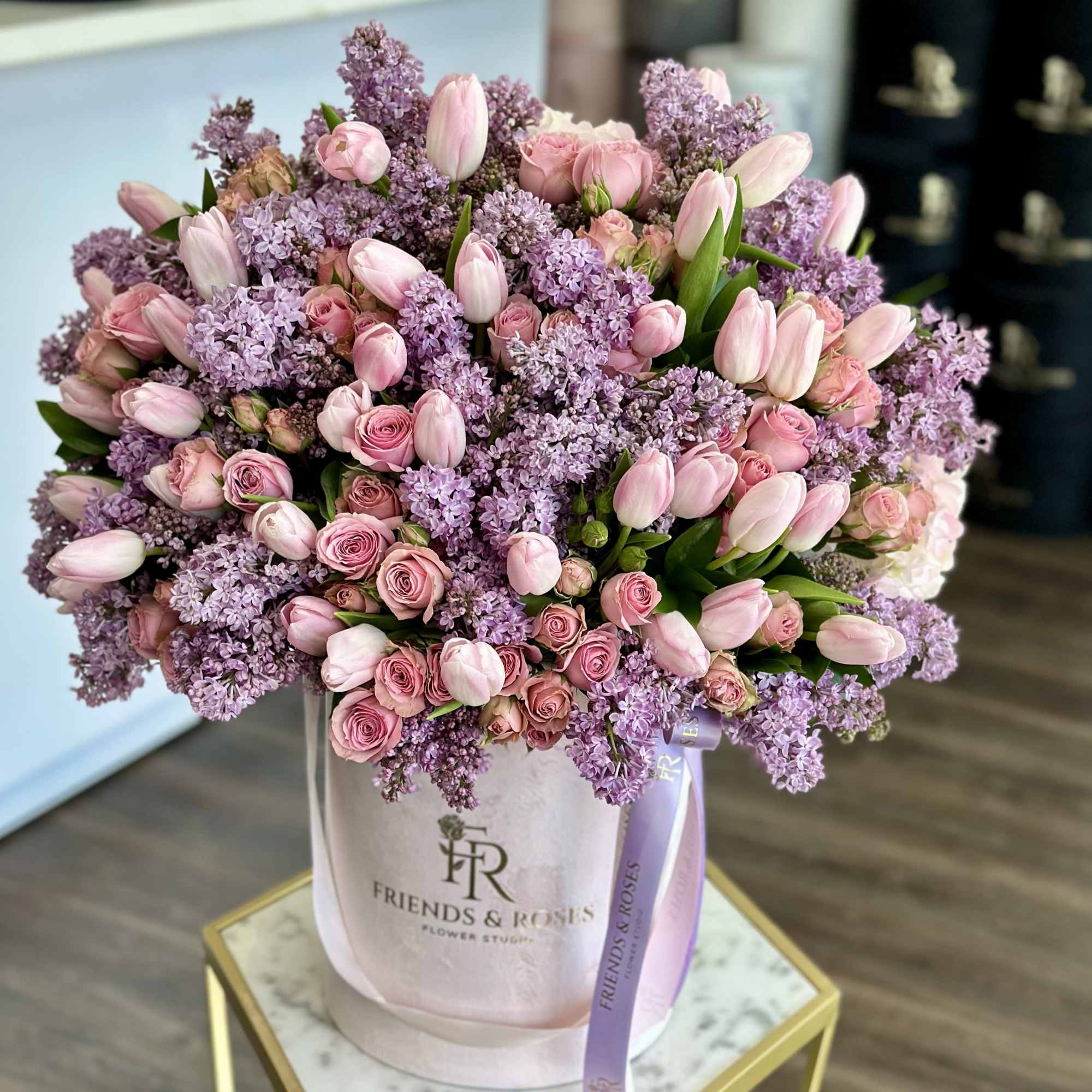 This arrangement is a soft, modern blend of tulips, lilacs, and roses