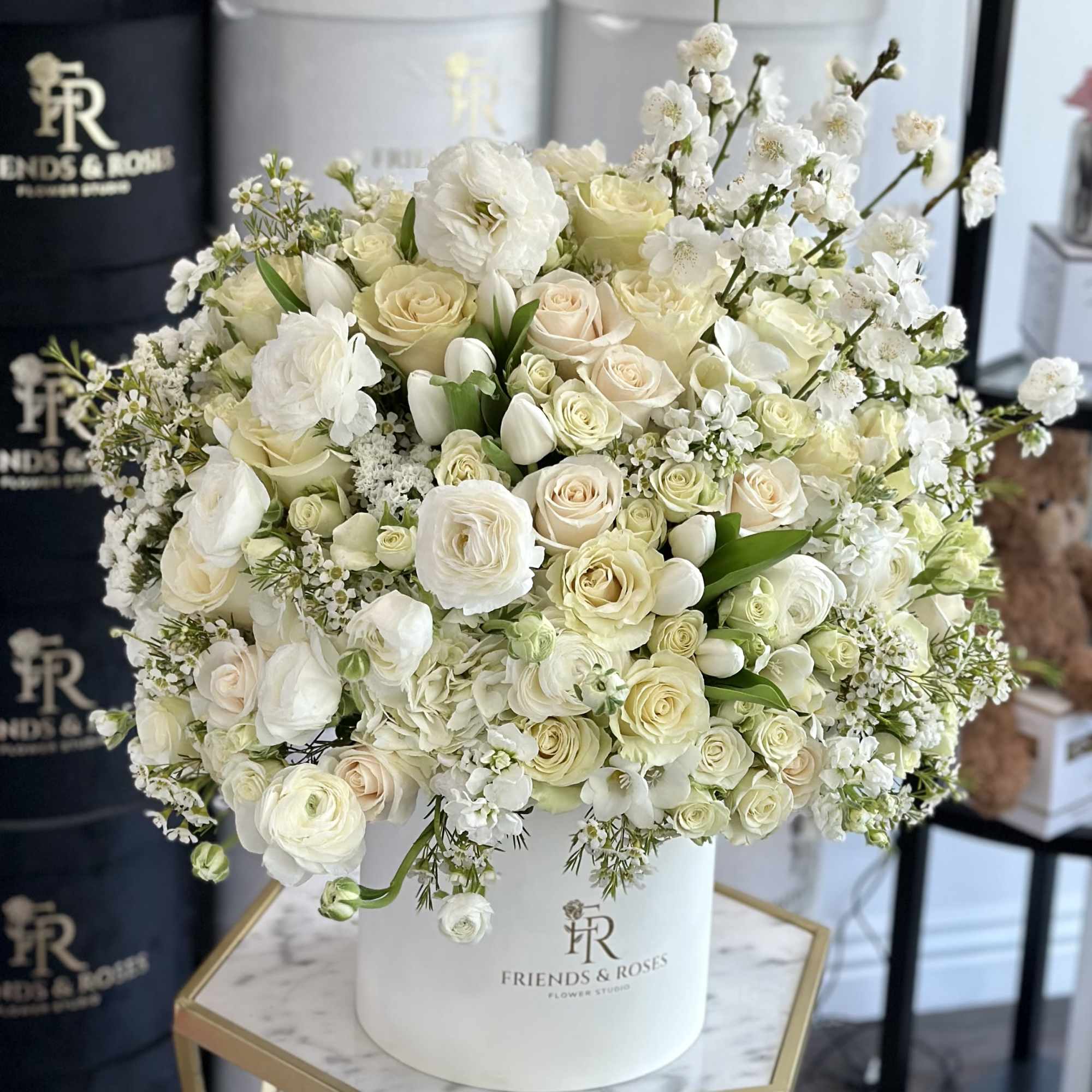The box contains a meticulously arranged selection of premium white flowers, each