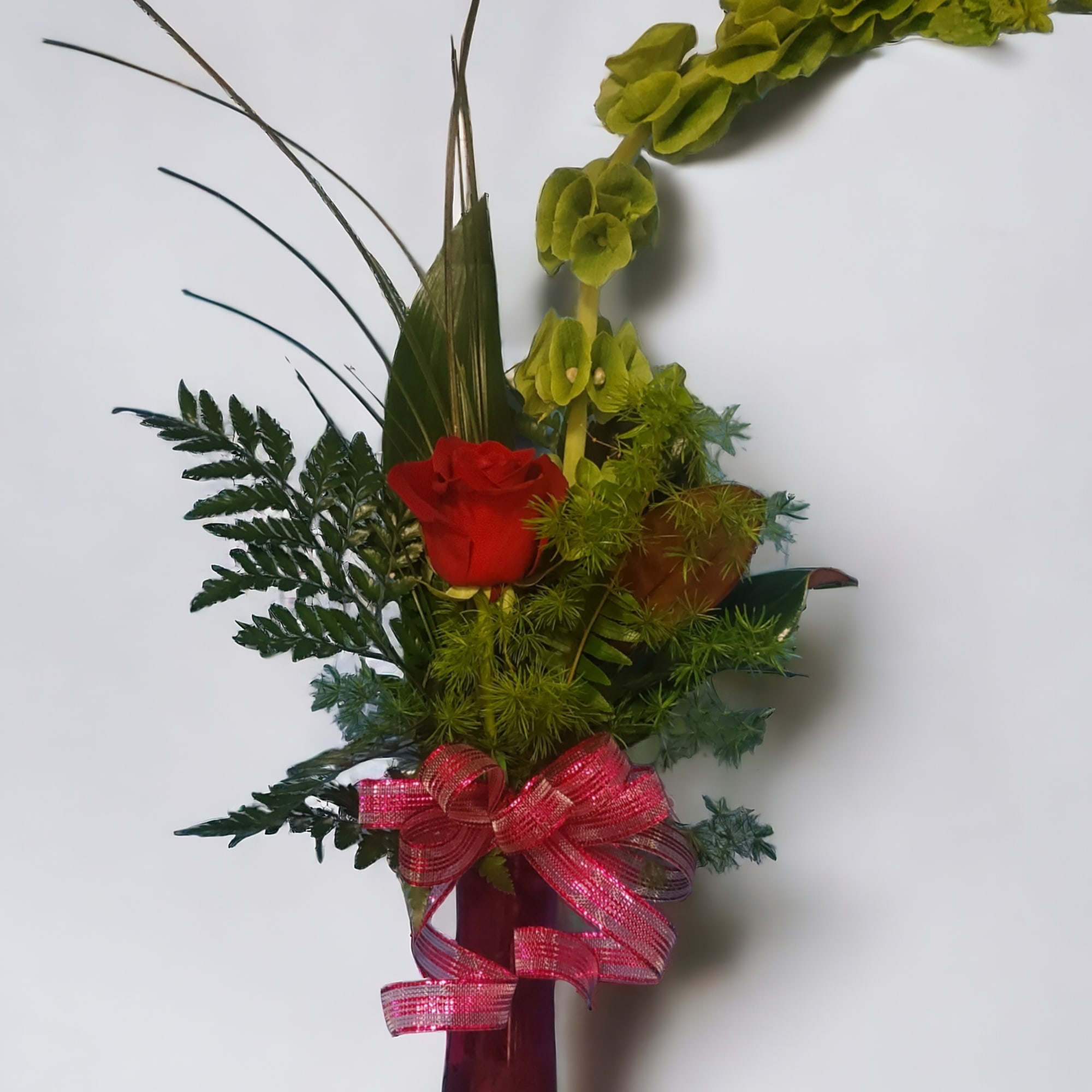 Roses and mixed foliage in a modern bud vase. 