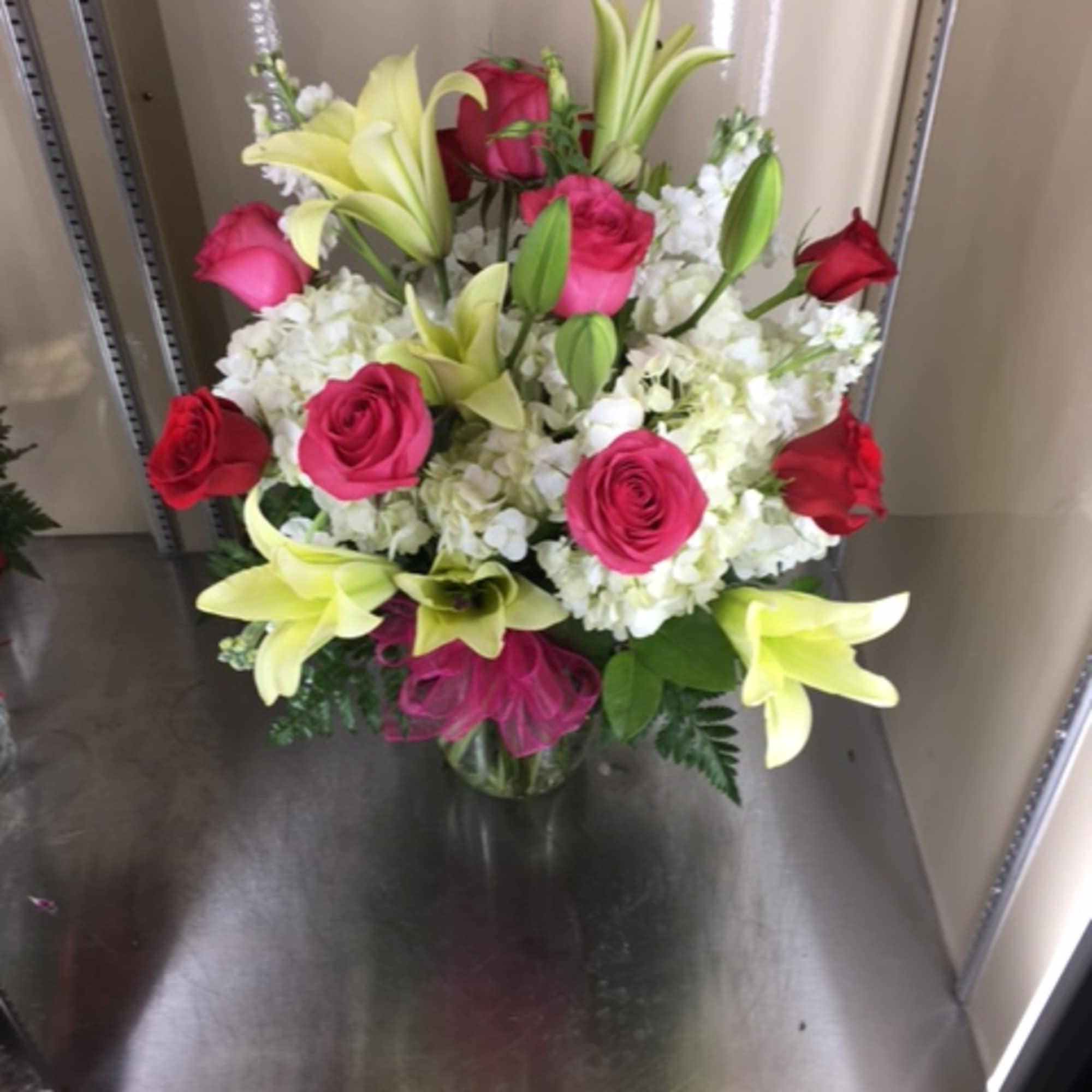 Mixed arrangement with lilies, pink rose, red roses, white hydrangea in a