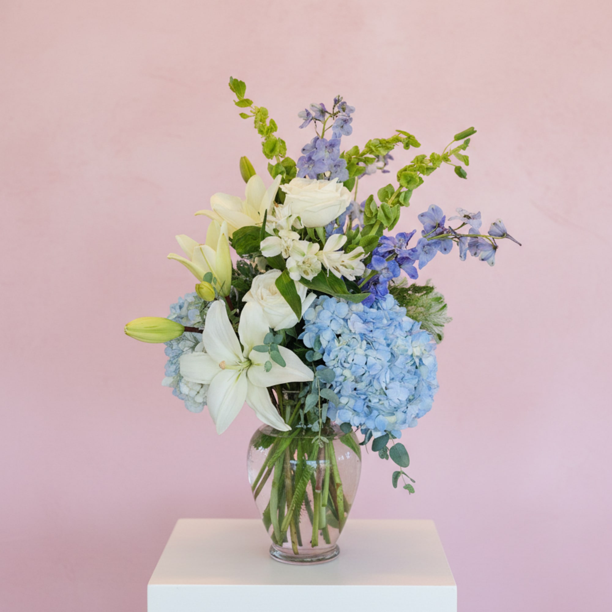 This arrangement contains delphinium, bells of ireland, asiatic lilies, hydrangea, blue iris