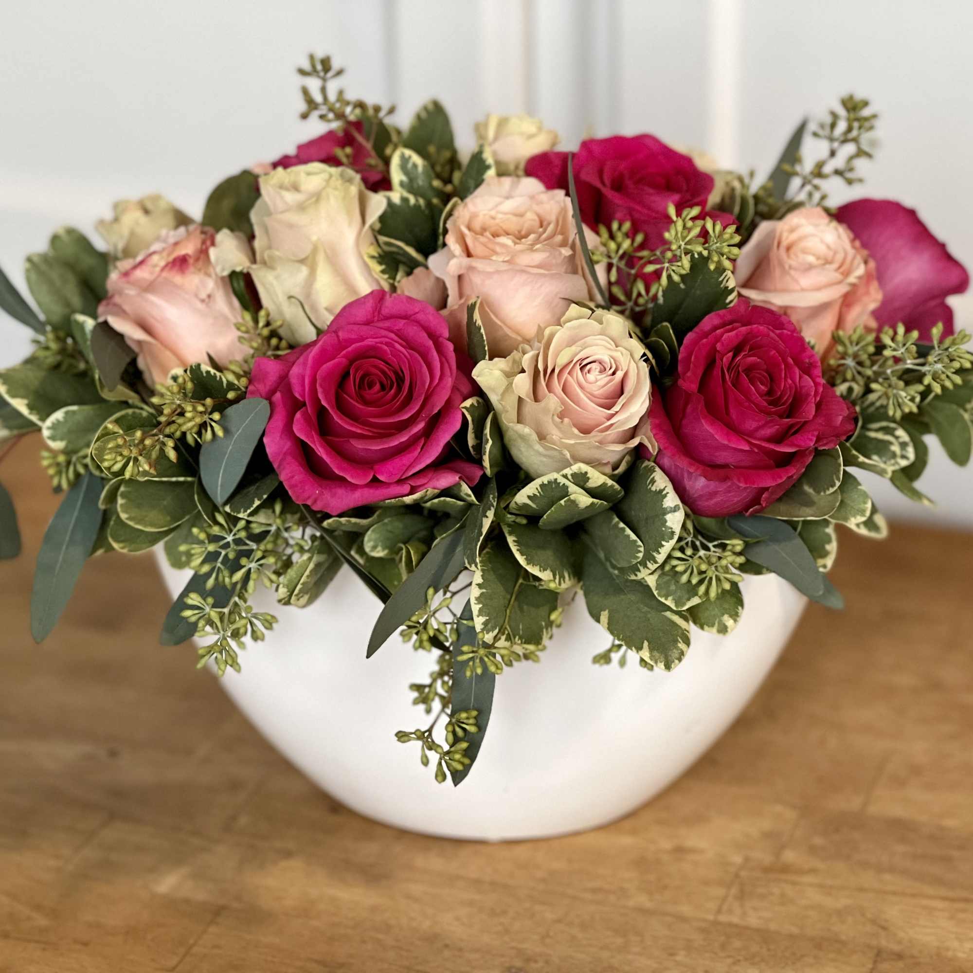 A low, lush, elegant arrangement of 15 assorted pink roses in a