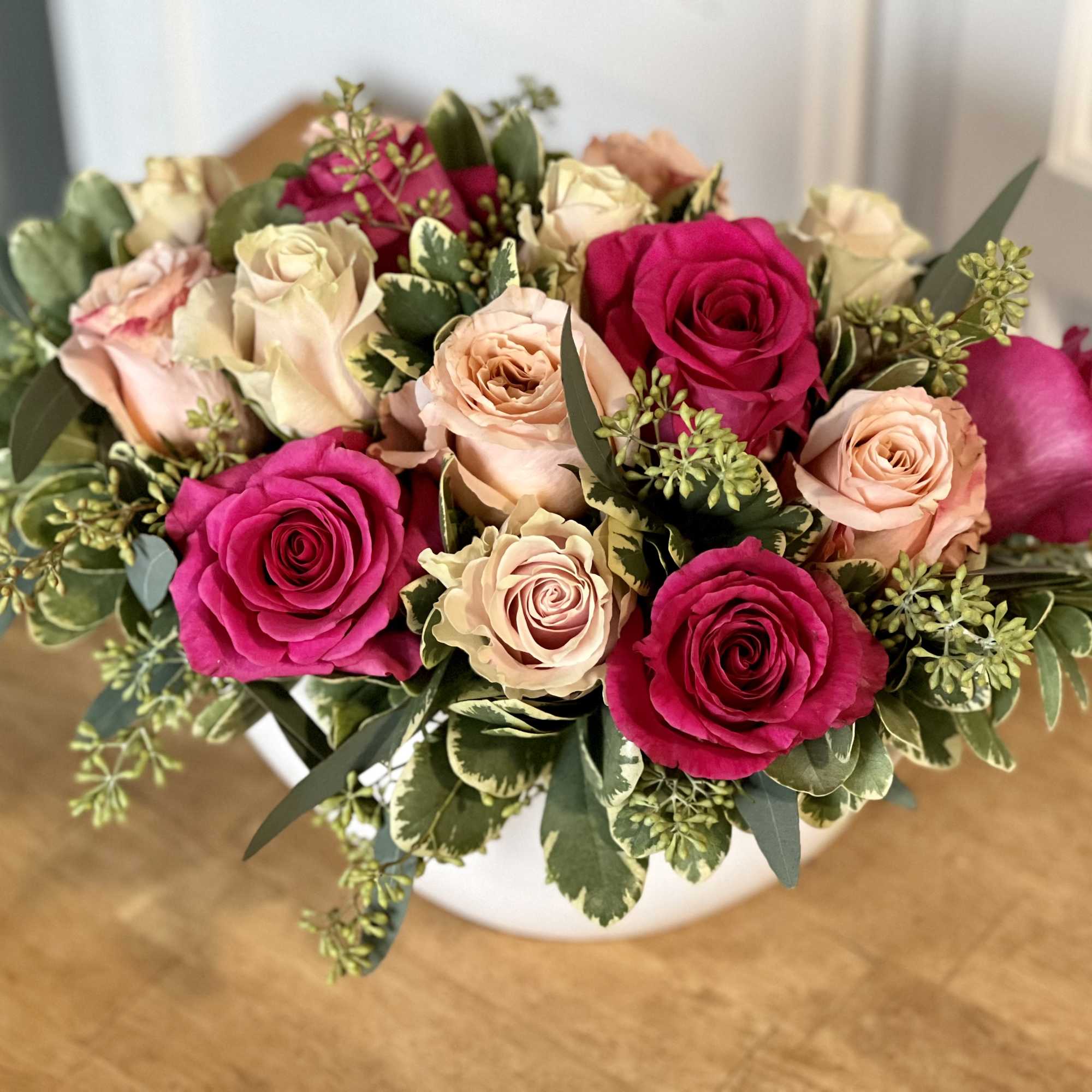 A low, lush, elegant arrangement of 15 assorted pink roses in a