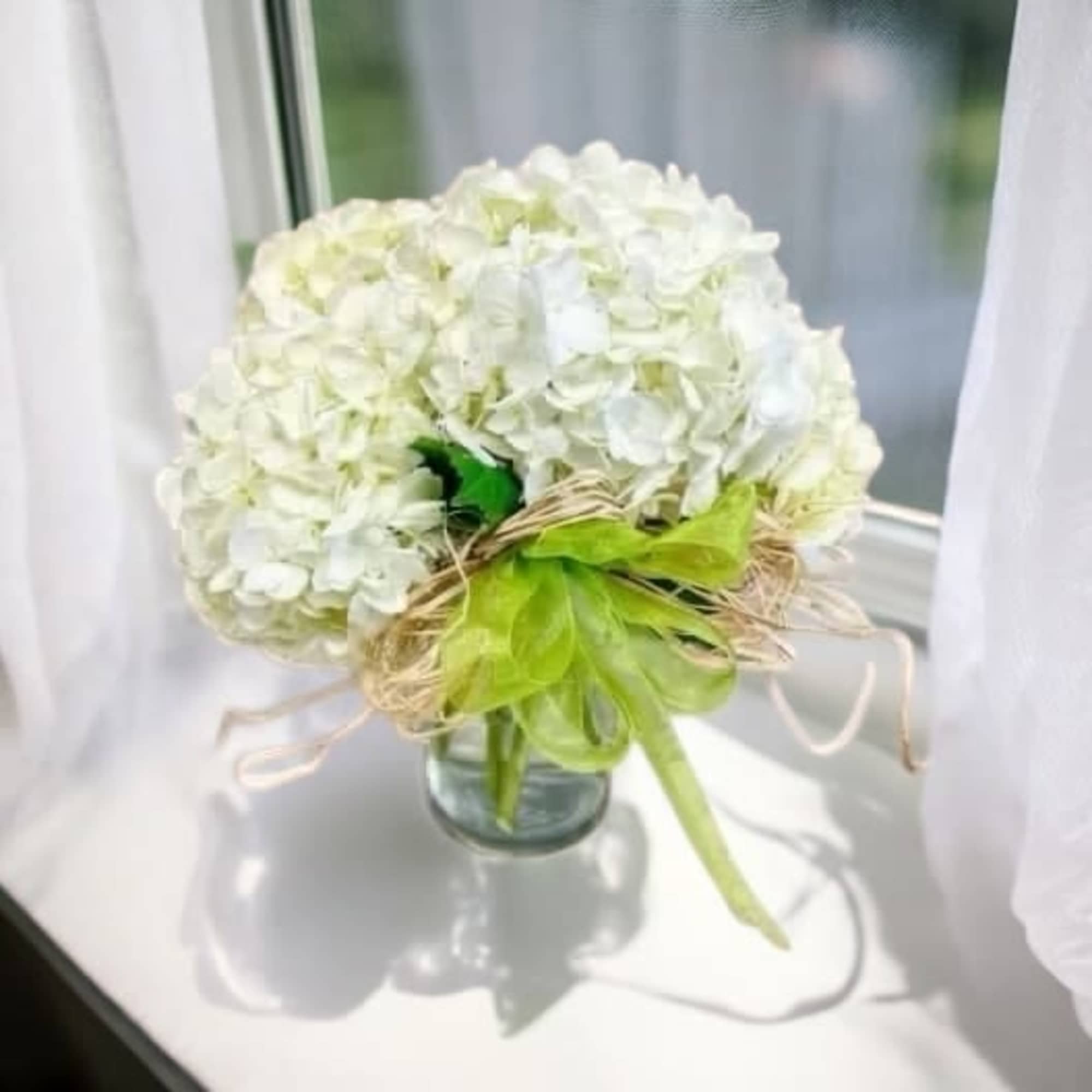 Hand gathered hydrangeas clustered together and placed in a cylinder vase accented