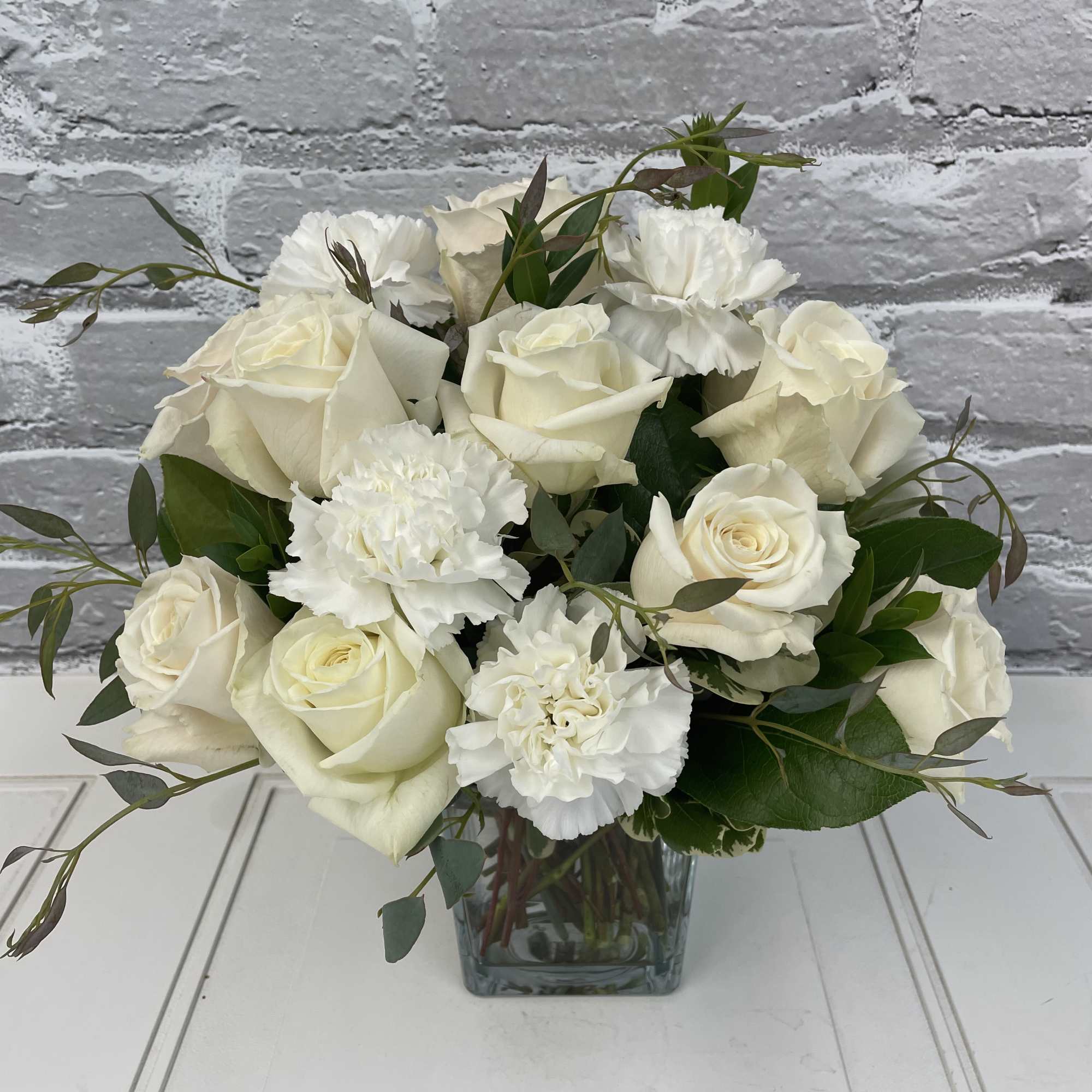 Lower compact design of white roses and white carnations.
