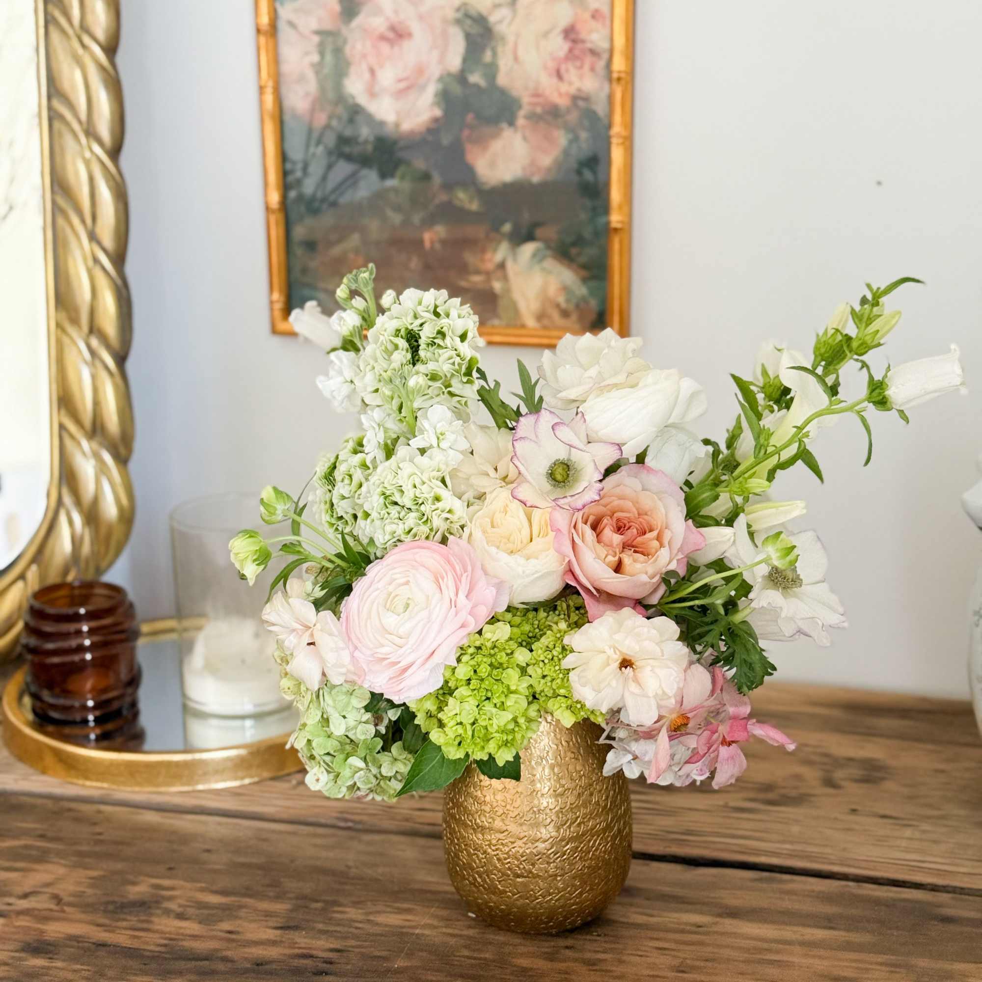 A seasonal lush mixed arrangement filled in a gold vase.  