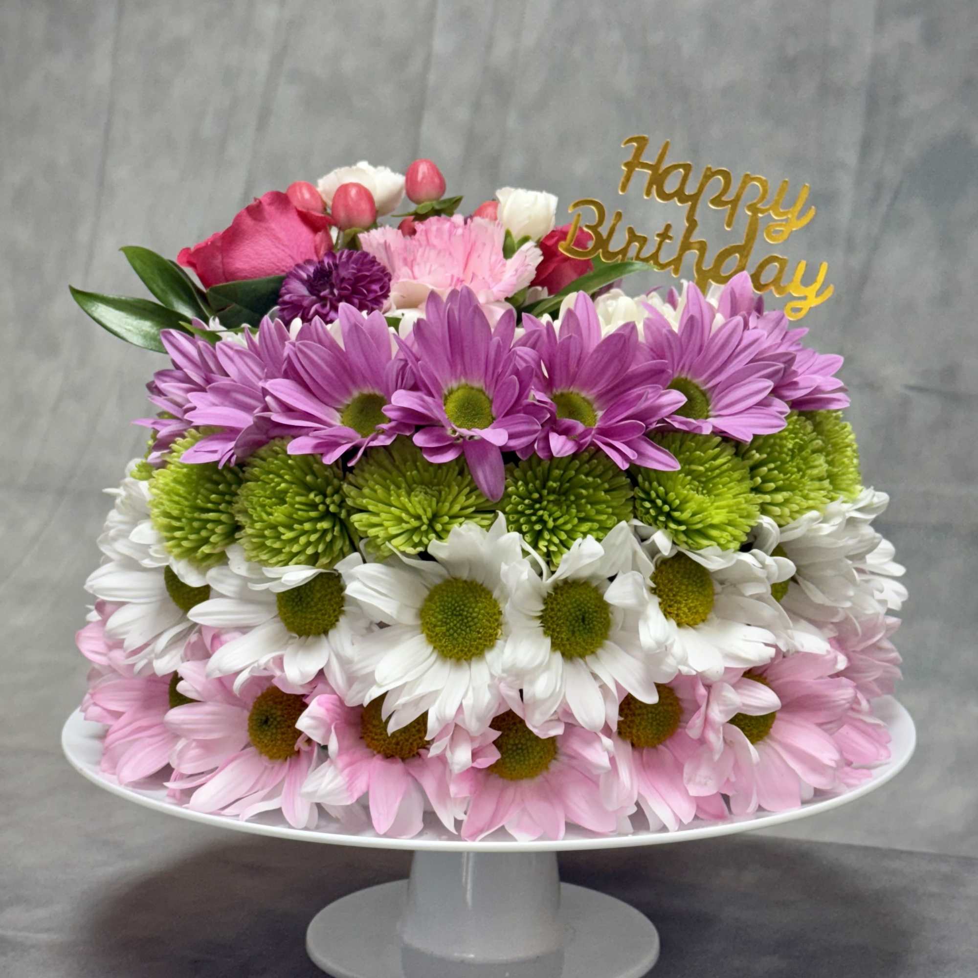 A dreamy, cake-shaped floral arrangement featuring soft pinks, delicate lavender, creamy whites