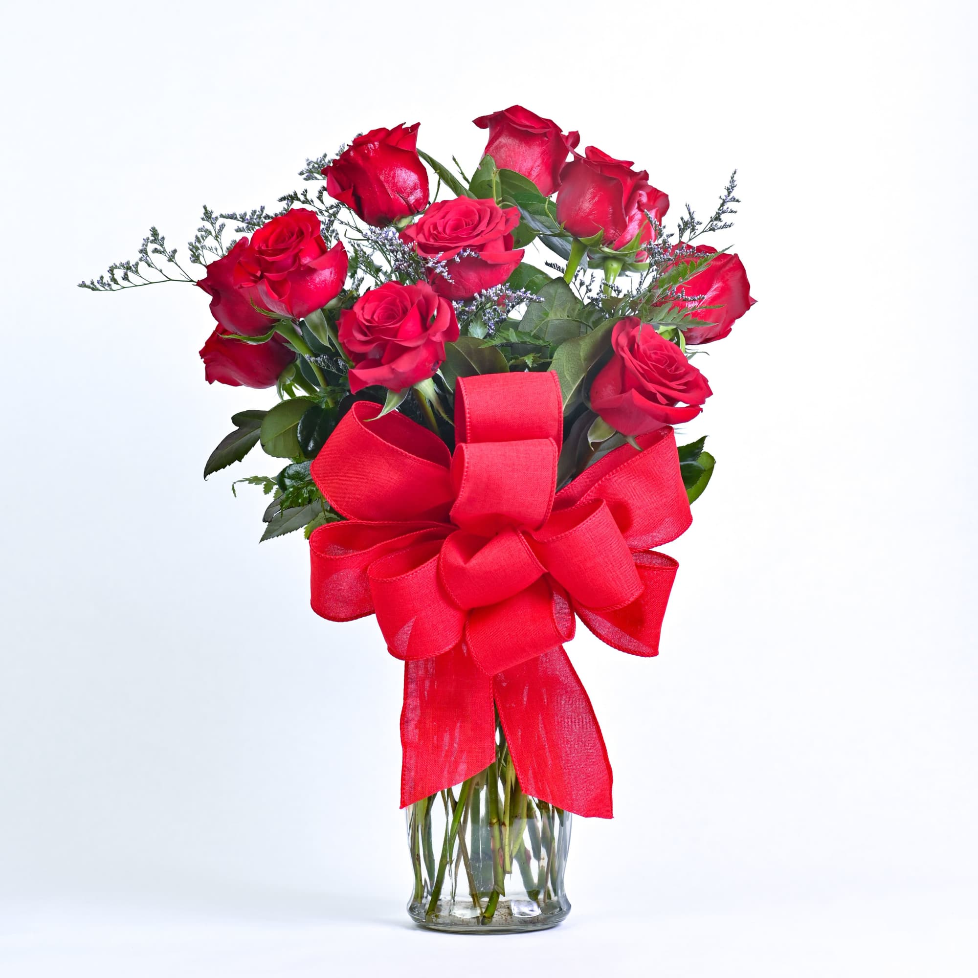 A stunning dozen red roses, artfully arranged with lush greenery and soft