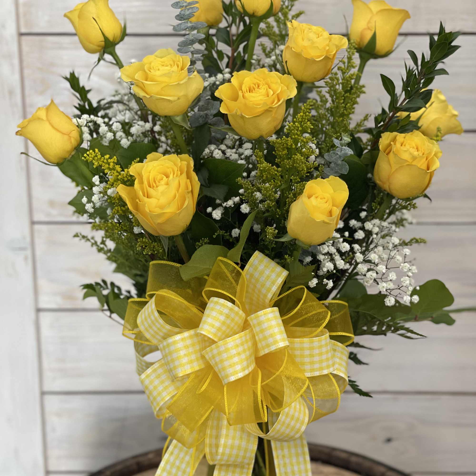 A dozen Bikini yellow roses arranged in a vase with filler flowers