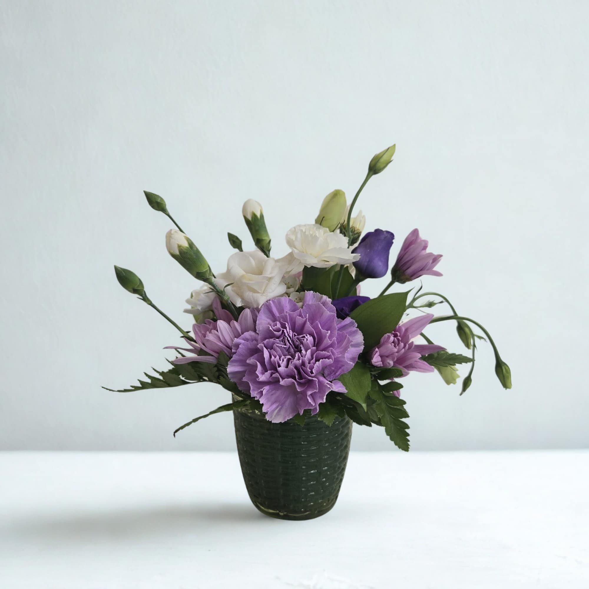 A thoughtfully designed mini arrangement created with fresh, seasonal blooms in a