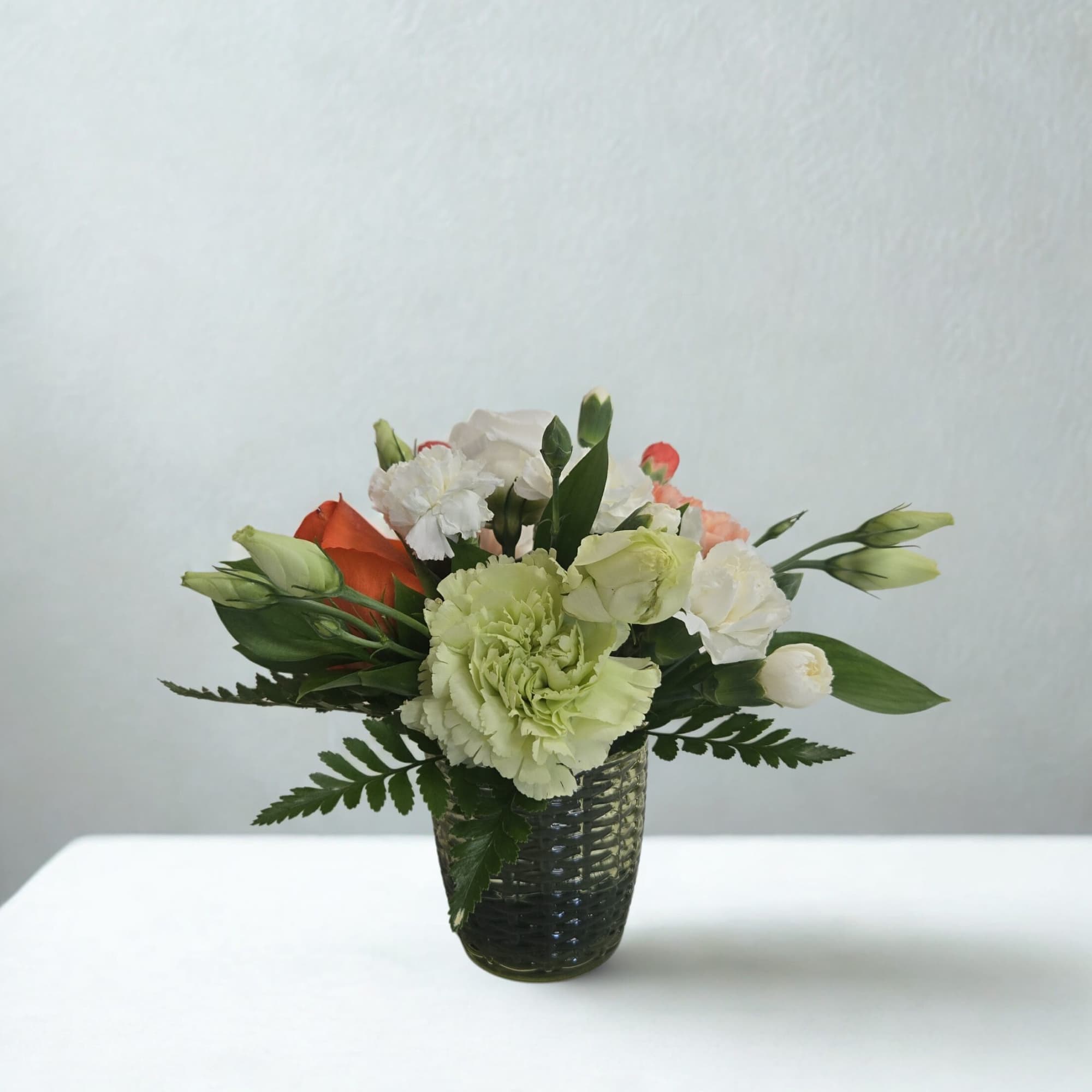 A thoughtfully designed mini arrangement created with fresh, seasonal blooms in a