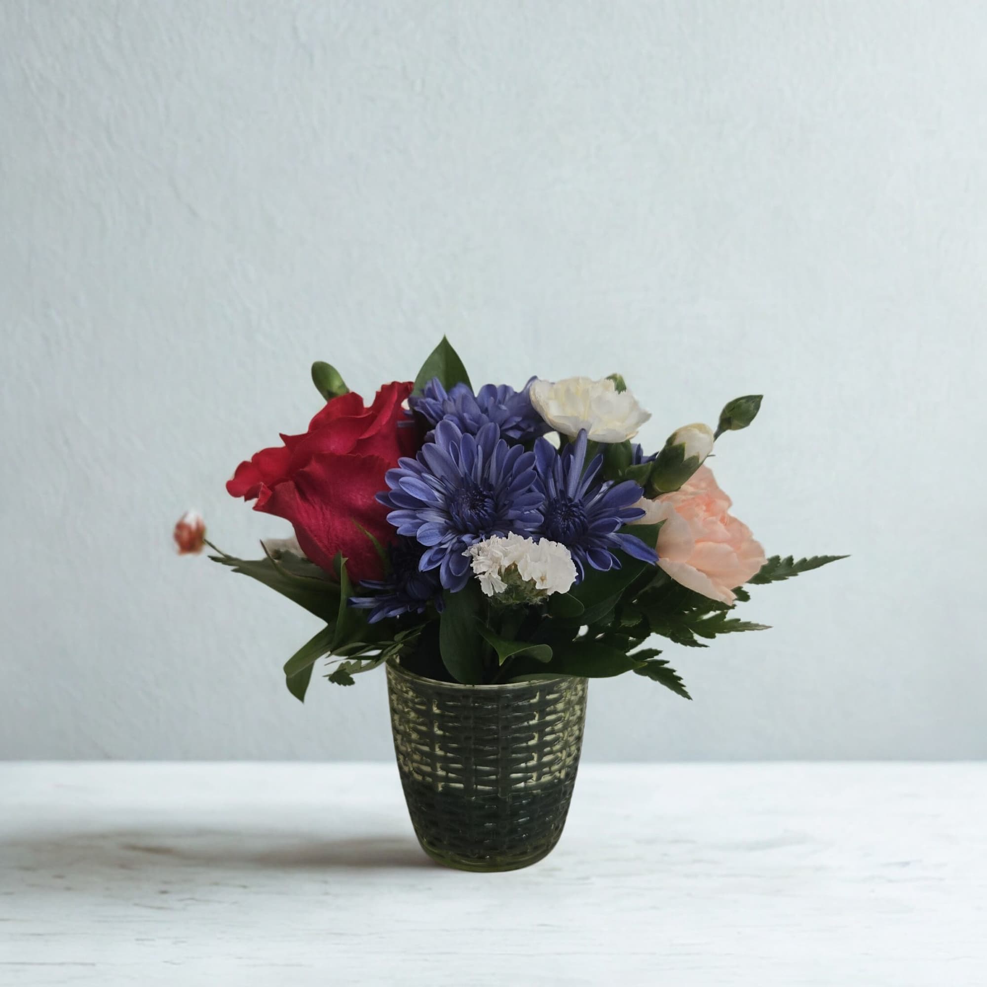 A thoughtfully designed mini arrangement created with fresh, seasonal blooms in a