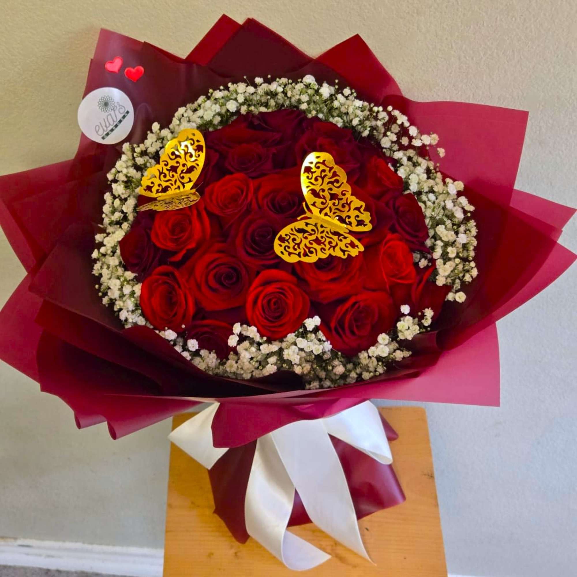 Beautiful wrapped bouquet with 24 red roses, golden butterflies, and a cloud