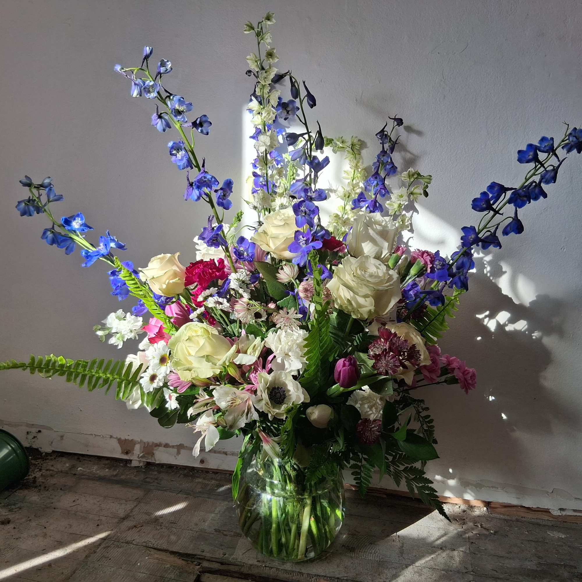 Beautiful charming crispy white roses, carnations and daisies, navy blue delphinium, burgundy