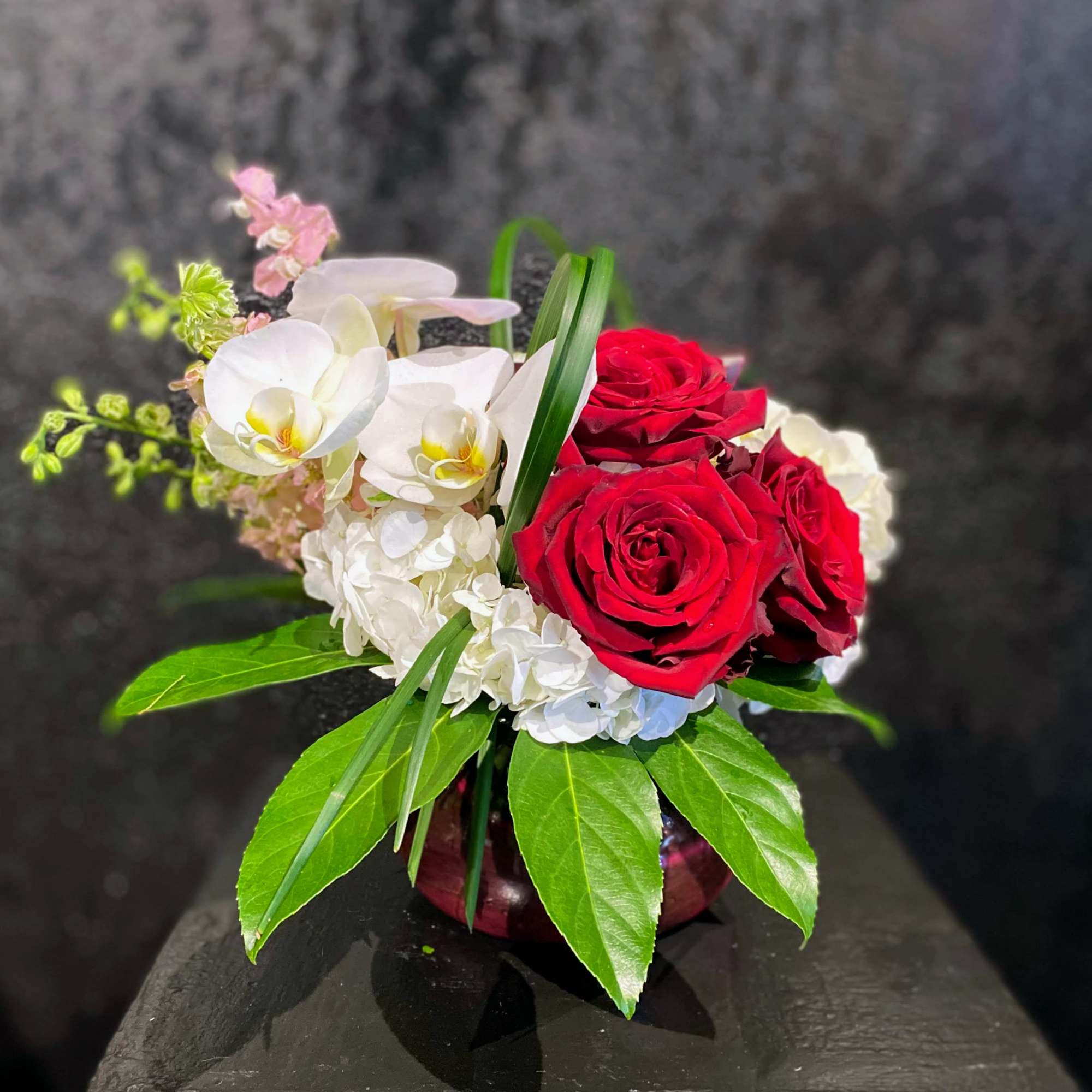 The perfect posy vase holds a cluster of red roses accented by