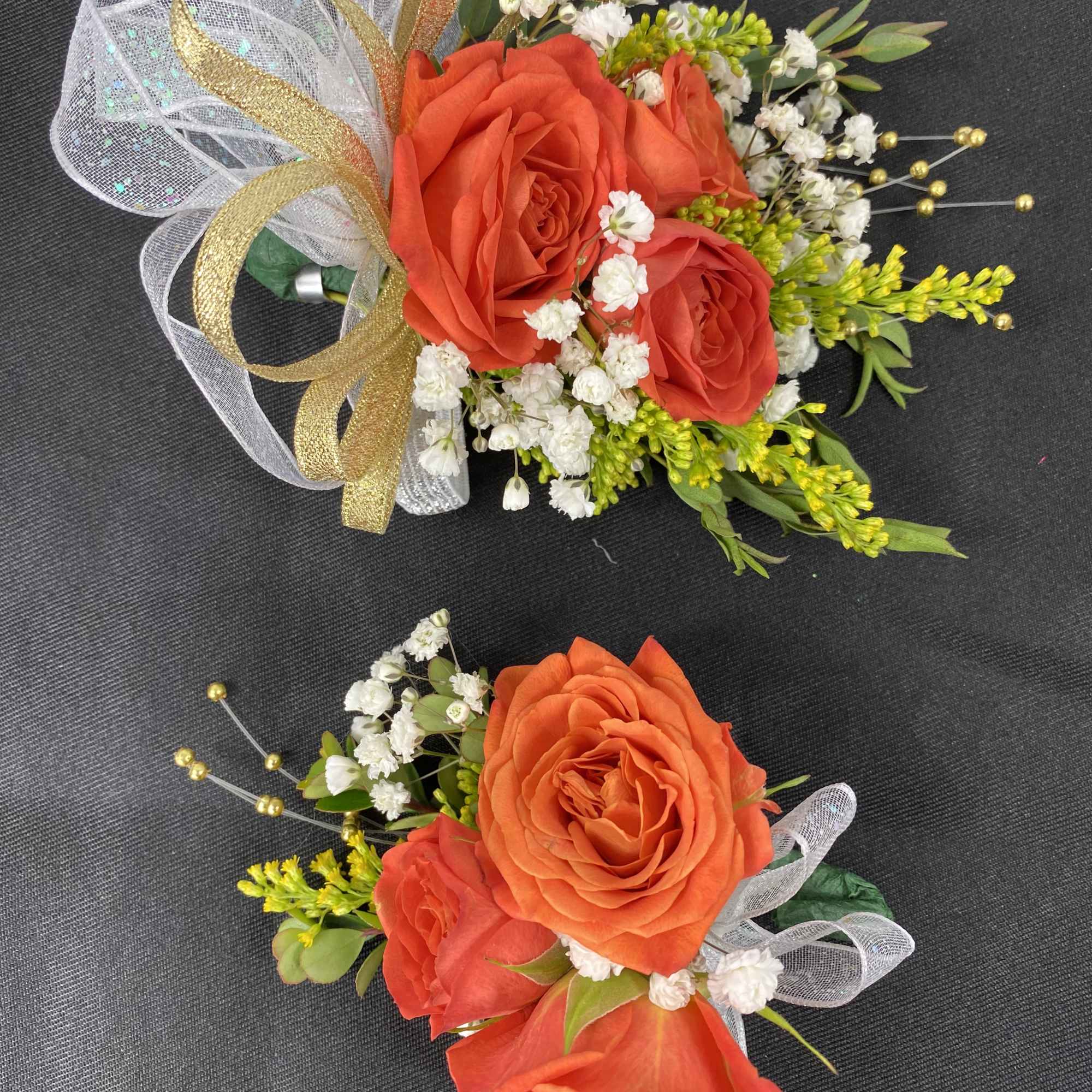 Orange roses, embellishments, with white and gold ribbon.

