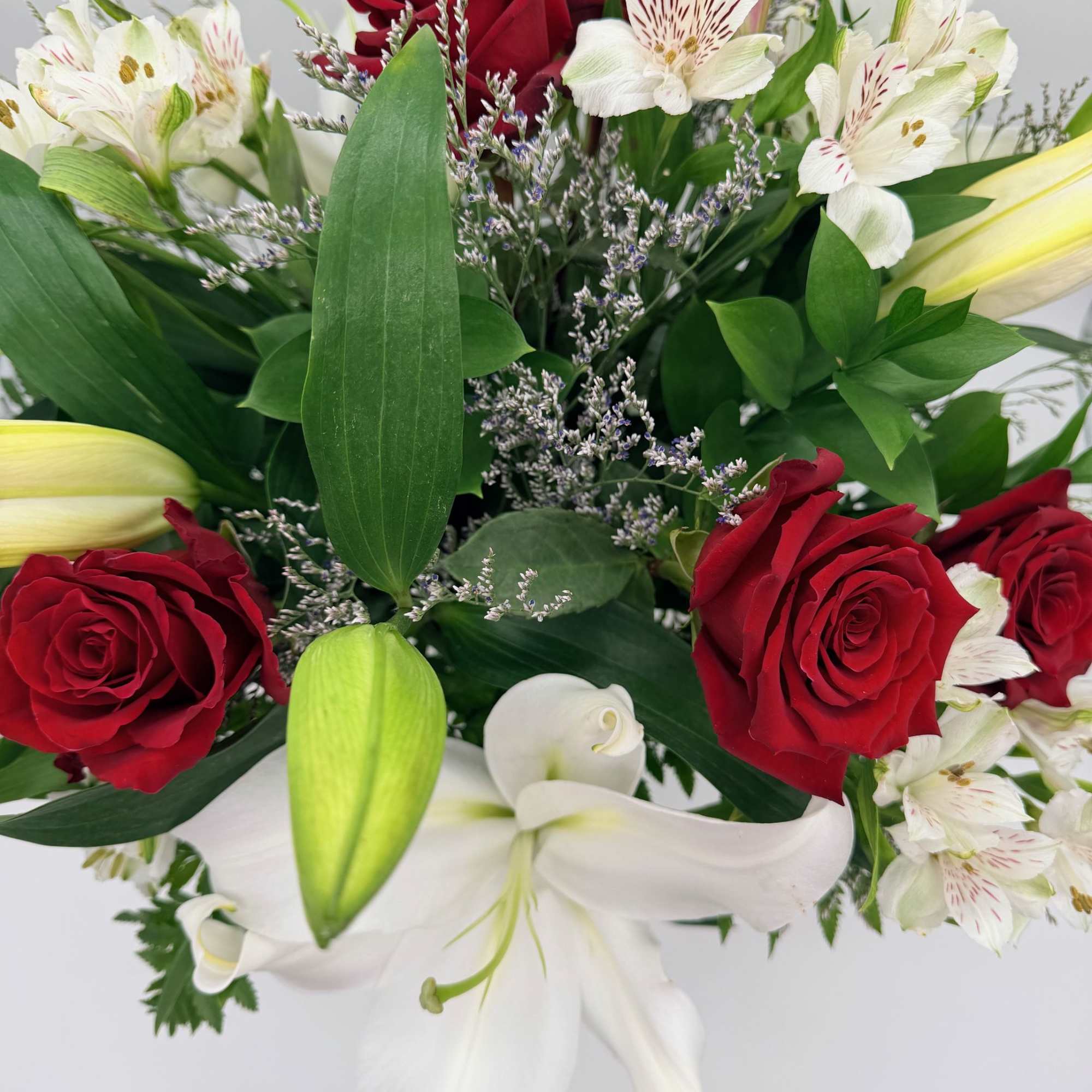 Sweet, classic, and endlessly romantic, red roses with soft white lilies and