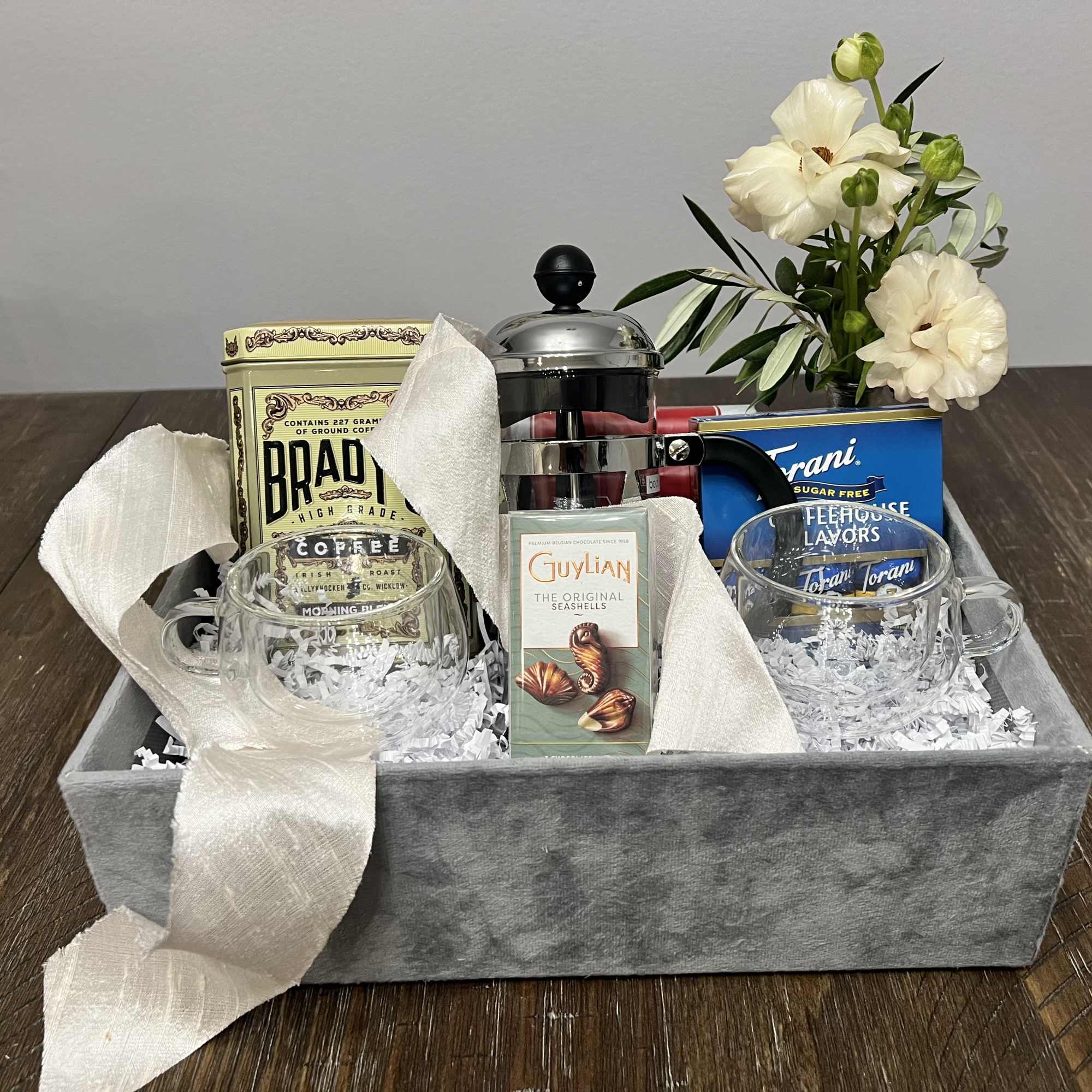 Box filled with a small seasonal arrangement, coffee, cookies, chocolates, coffee flavors