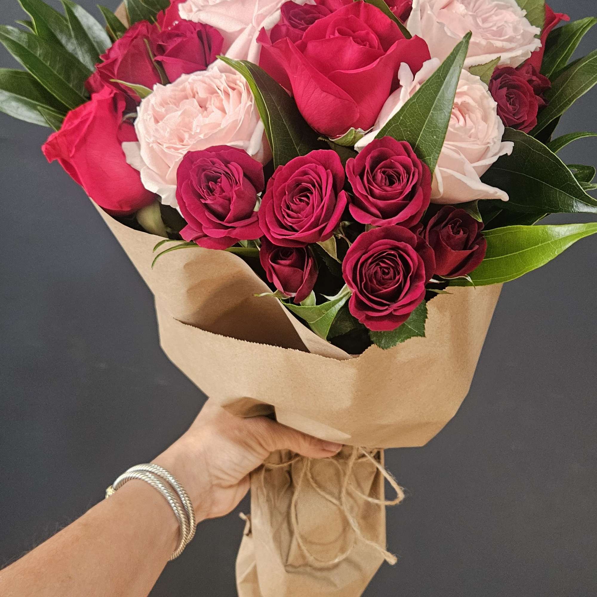 A beautiful wrapped arrangement Of six red roses, six fragrant garden pink