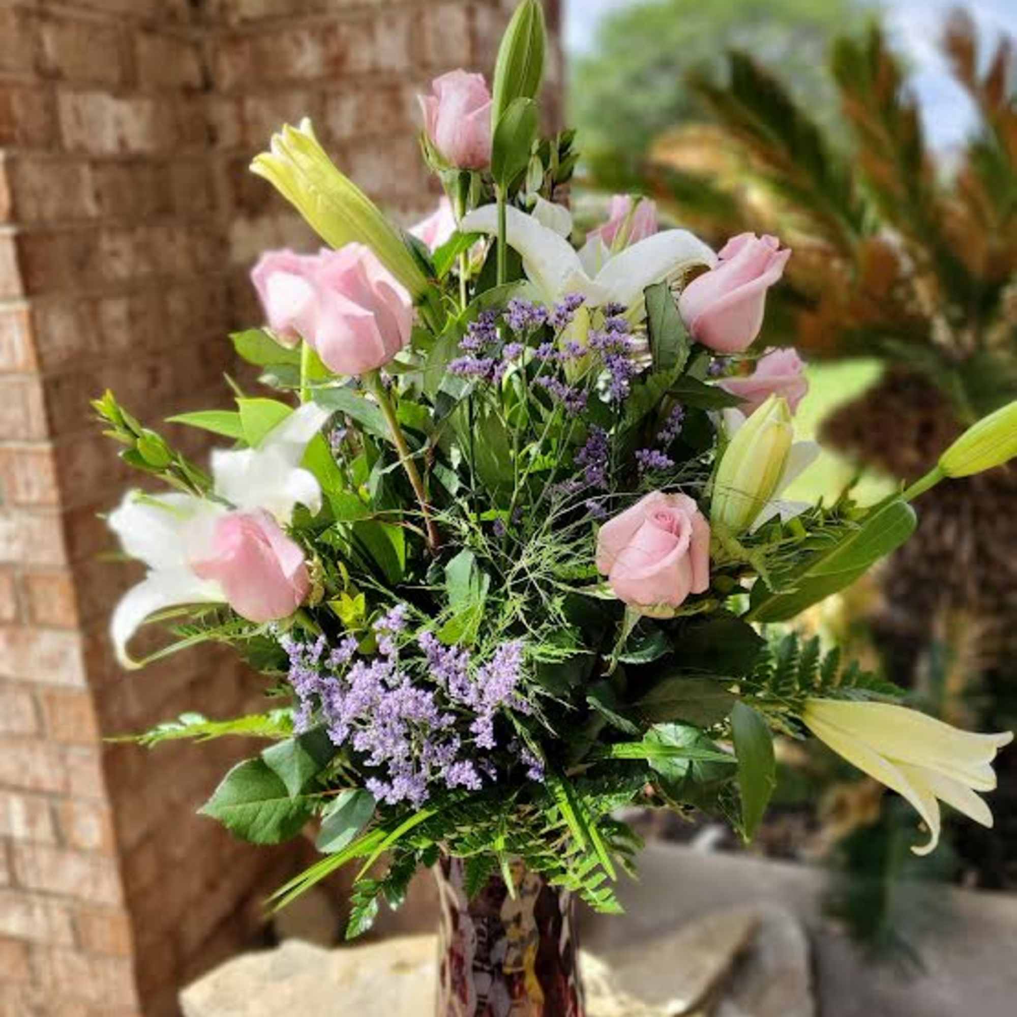 Twelve long-stemmed premium pink roses designed in a vase with complimenting lush