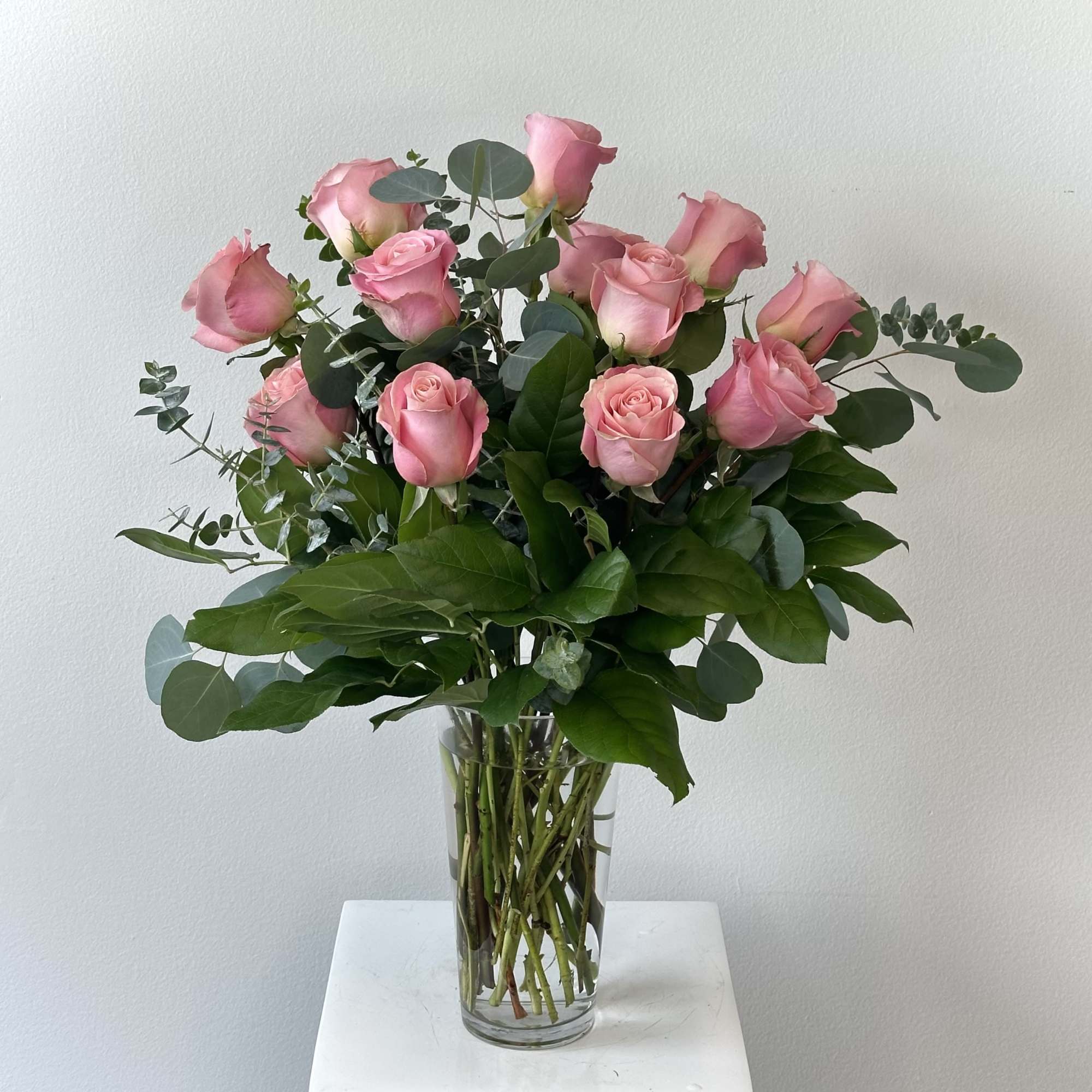 This arrangement is one dozen premium pink roses with greenery added to