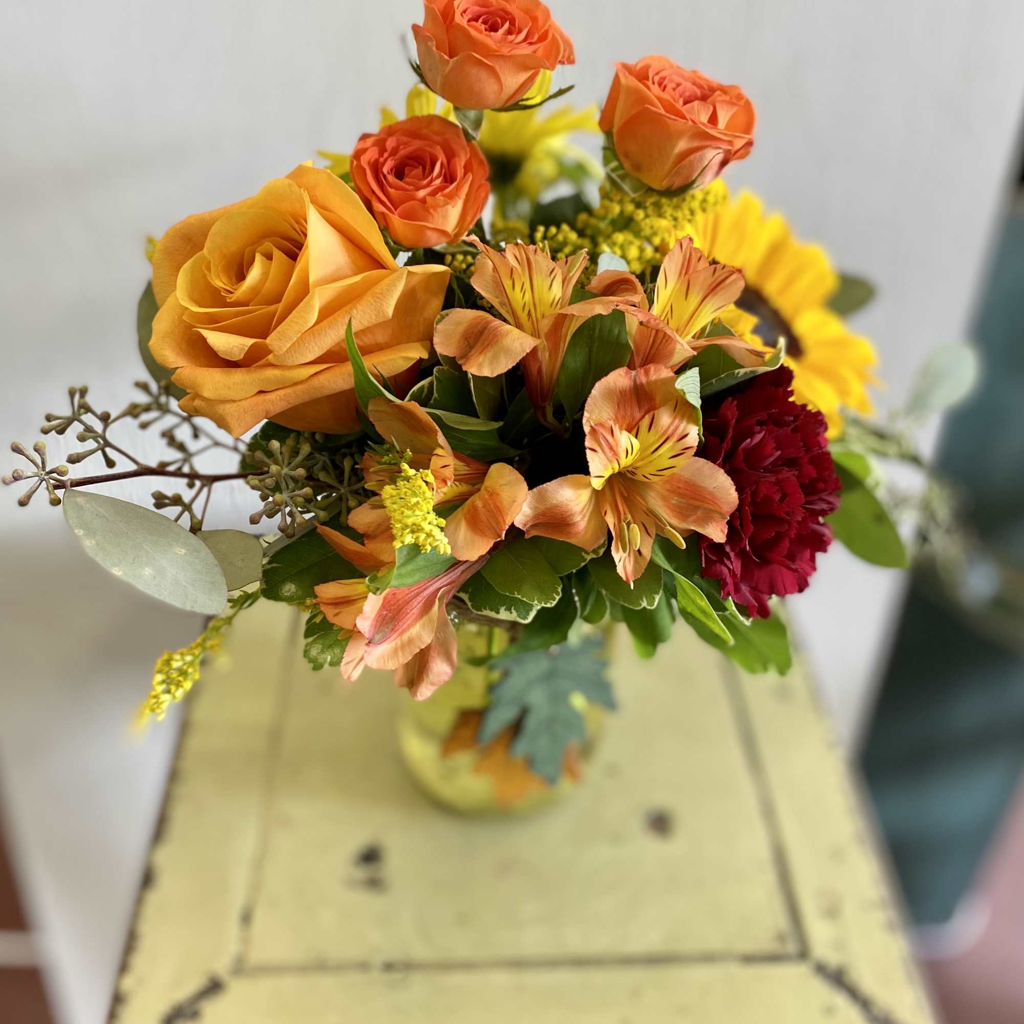 Roses, spray roses, carnations, seeded eucalyptus, and mums, all nestled together to