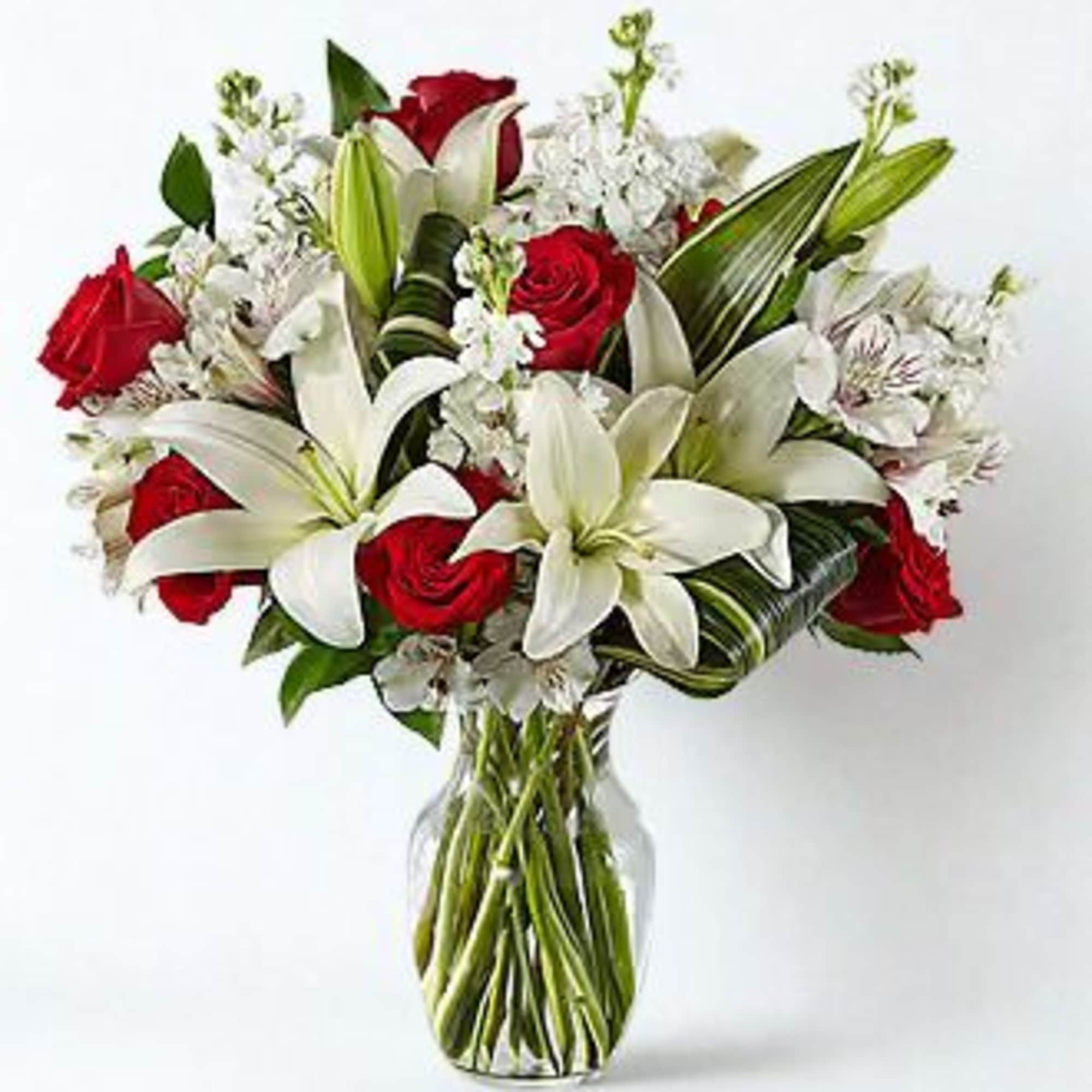 A stunning floral arrangement featuring lush red roses, elegant white lilies, and