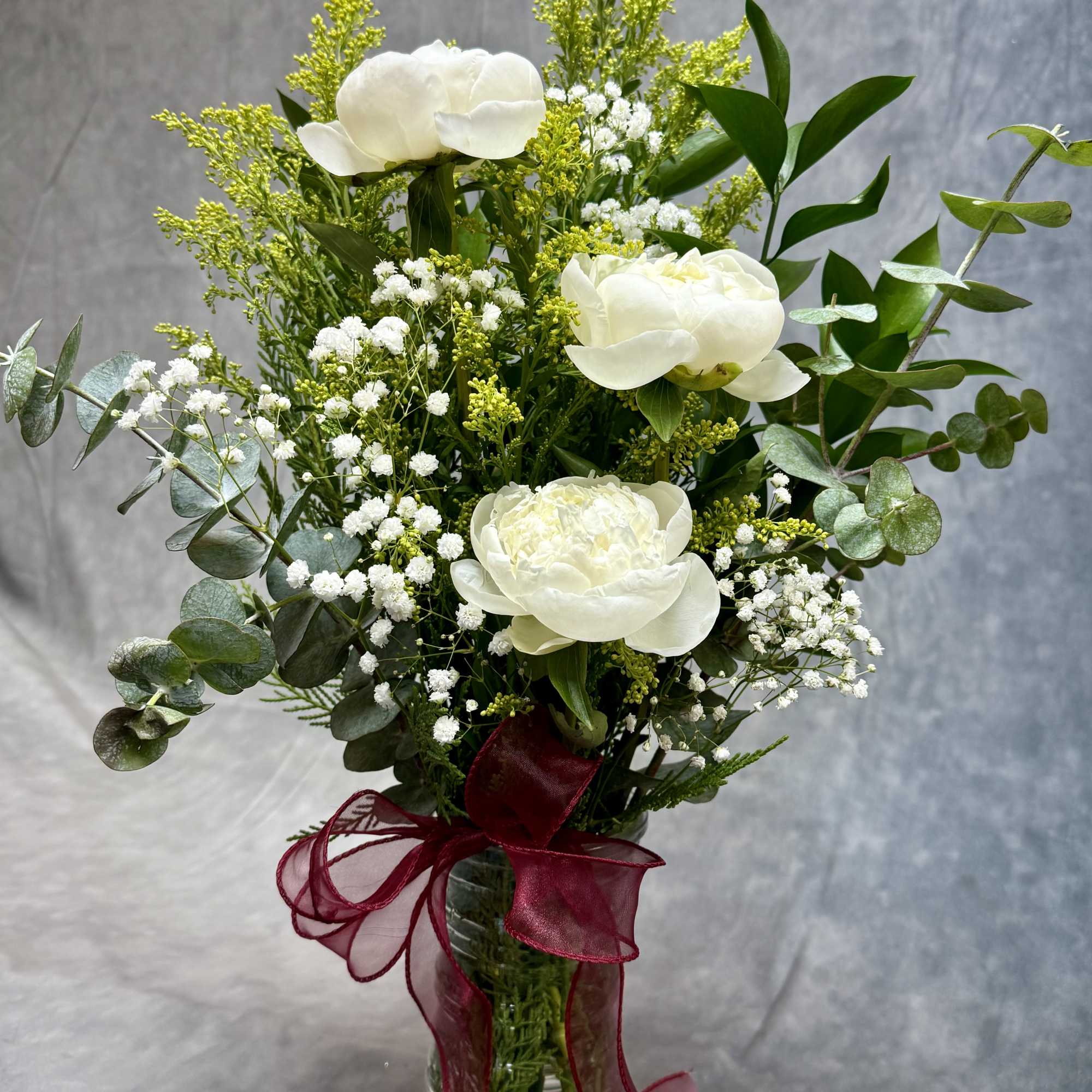 A dreamy vase filled with lush peonies, soft baby&rsquo;s breath, golden aster