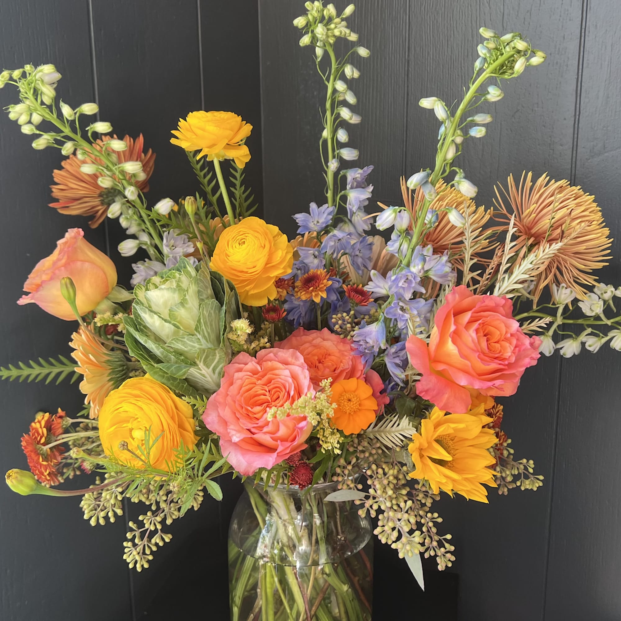 Seasonal, colorful flowers and foliage artfully arranged in a clear glass vase.

Year