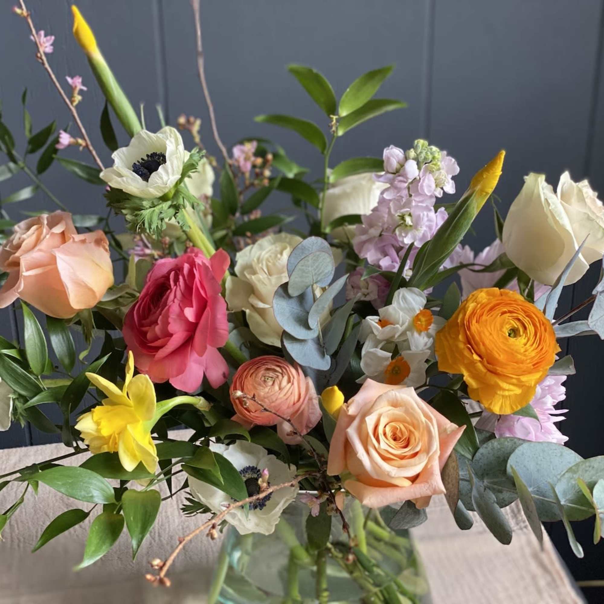 Seasonal, colorful flowers and foliage artfully arranged in a clear glass vase.

Year
