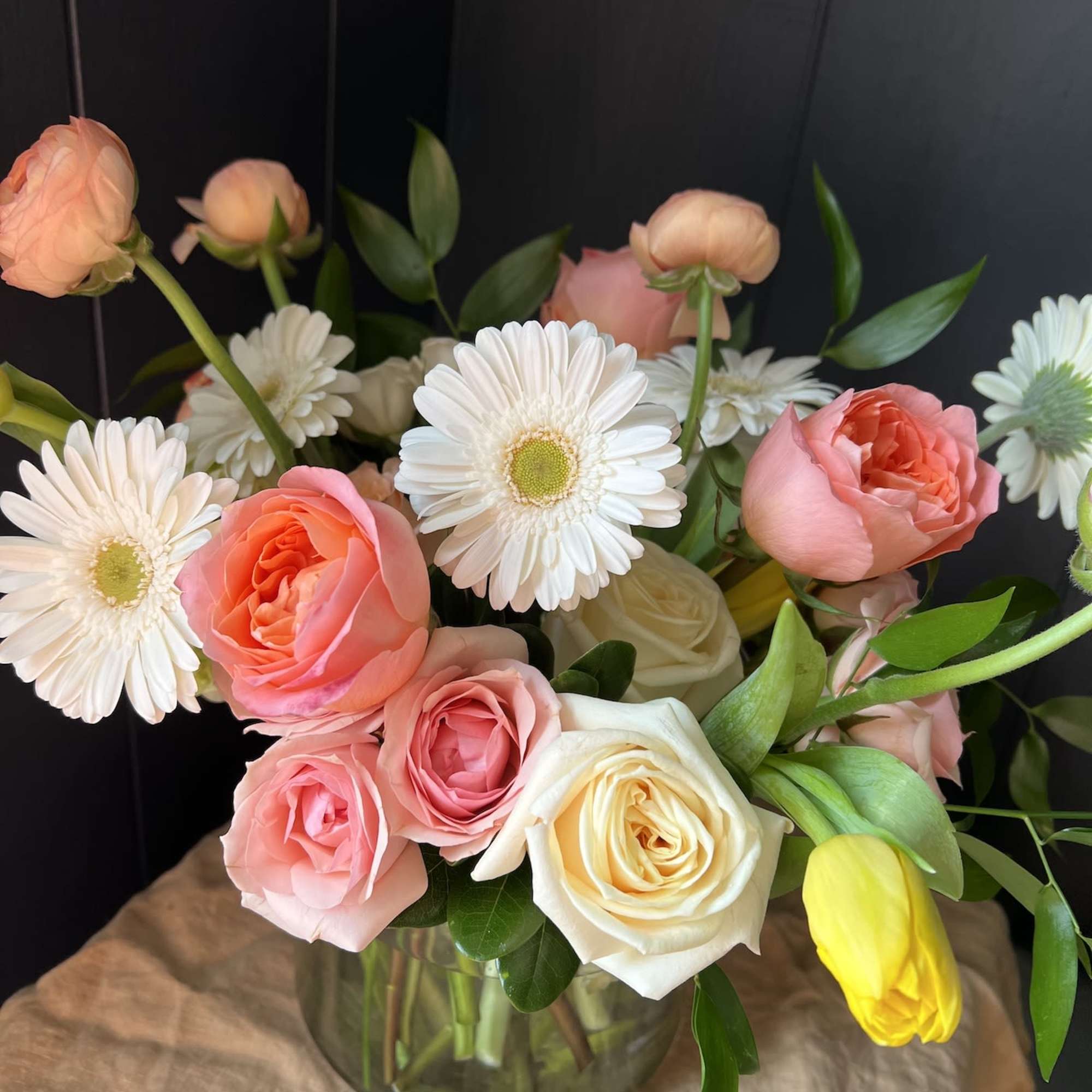 Seasonal, colorful flowers and foliage artfully arranged in a clear glass vase.

Year