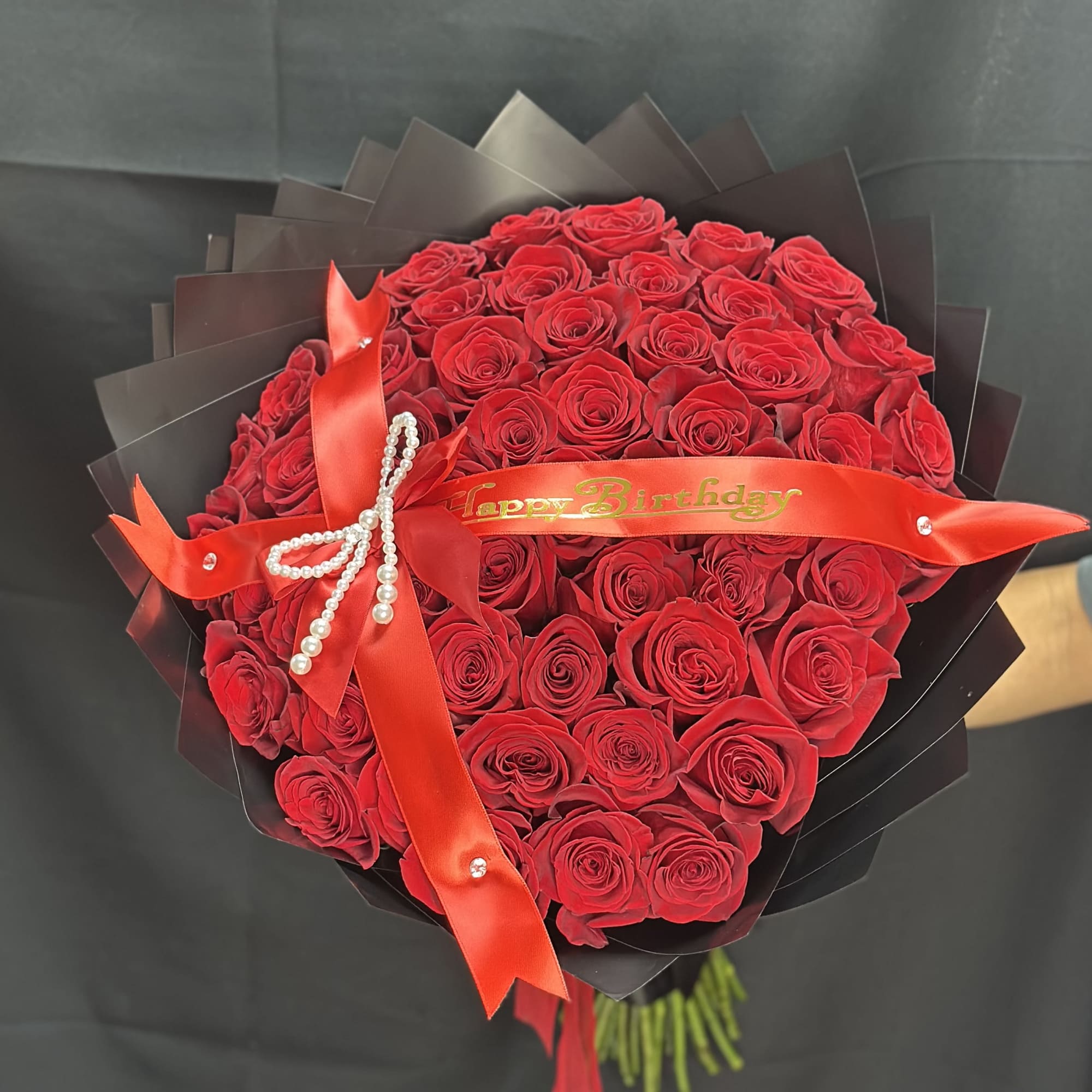 50 roses arranged into a round bouquet with the color paper of